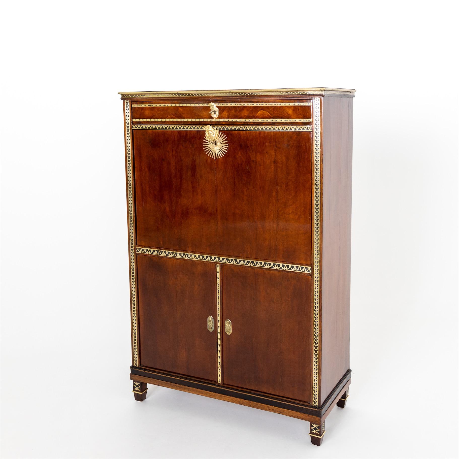 Secretaire, veneered in mahogany and decorated with pierced brass bands along the pilasters and traverses. The two-door base cabinet is also decorated with brass banding along the centre stile and features brass hardware as keyhole covers in the