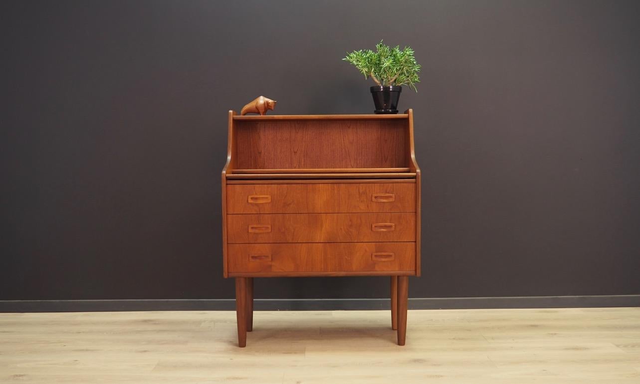 Original secretary from the 1960s-1970s, Minimalist form, Danish design. Surface veneered with teak. The furniture has a sliding top, and three capacious drawers. In addition, the tabletop can be raised, and under the mirror is hidden. Preserved in
