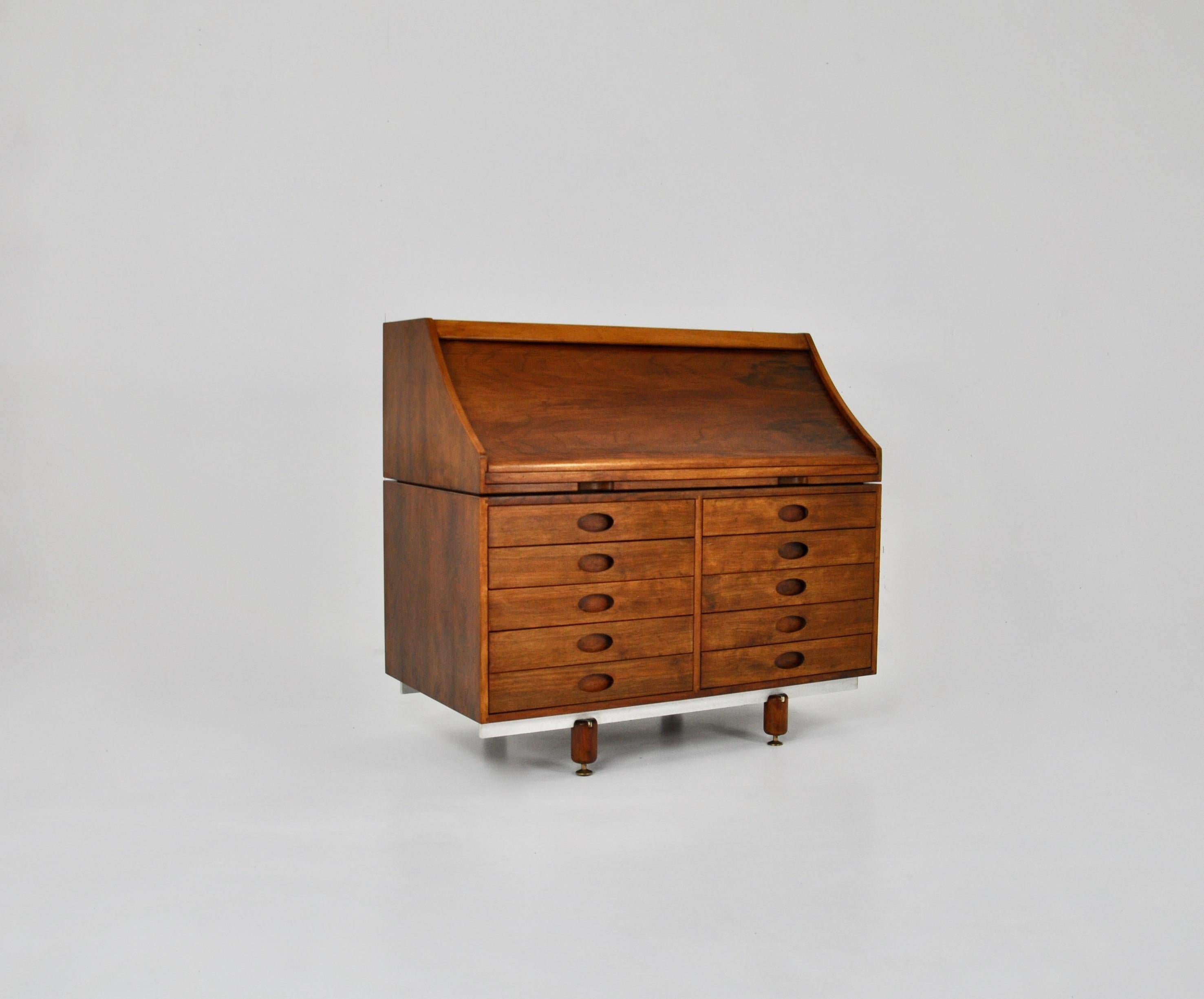 Wood and metal secretary. The roll top opens by pulling on the leather inlaid writing surface, under which are small drawers and a sliding door also containing drawers. This secretary has 10 drawers in the front. The legs are made of solid wood and