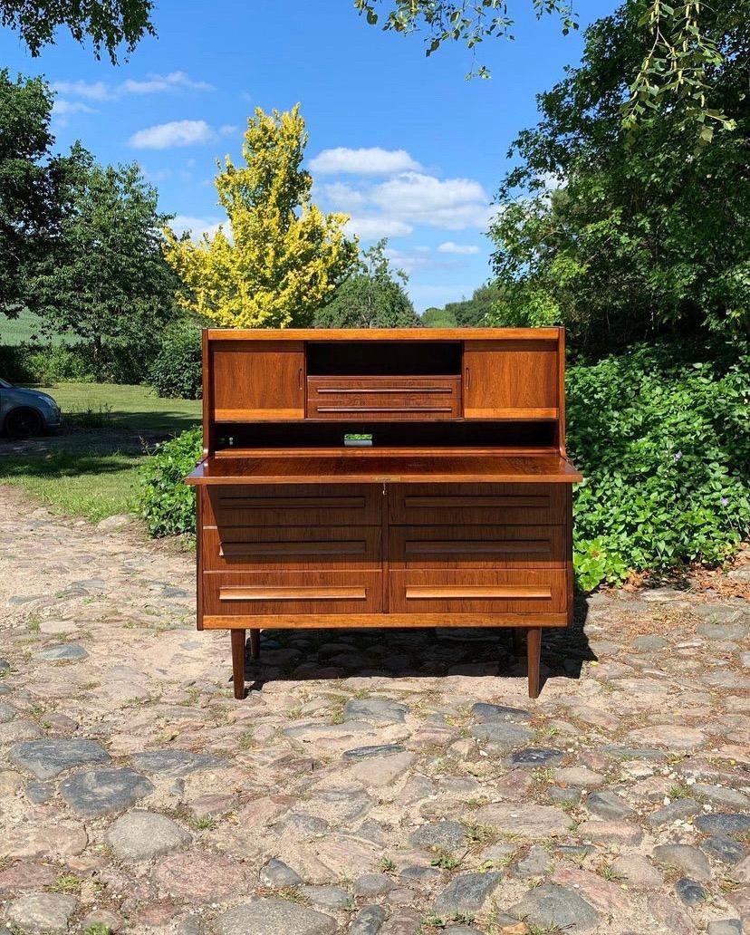 Beautiful secretary desk by Sigfred Omann in rosewood. Features 6 drawers, a drop-down surface with storage space and a hidden room!! Key incl.
In a good condition. The front is a little faded by the sun (see pictures)

H. 115 cm. B. 115 cm. D.