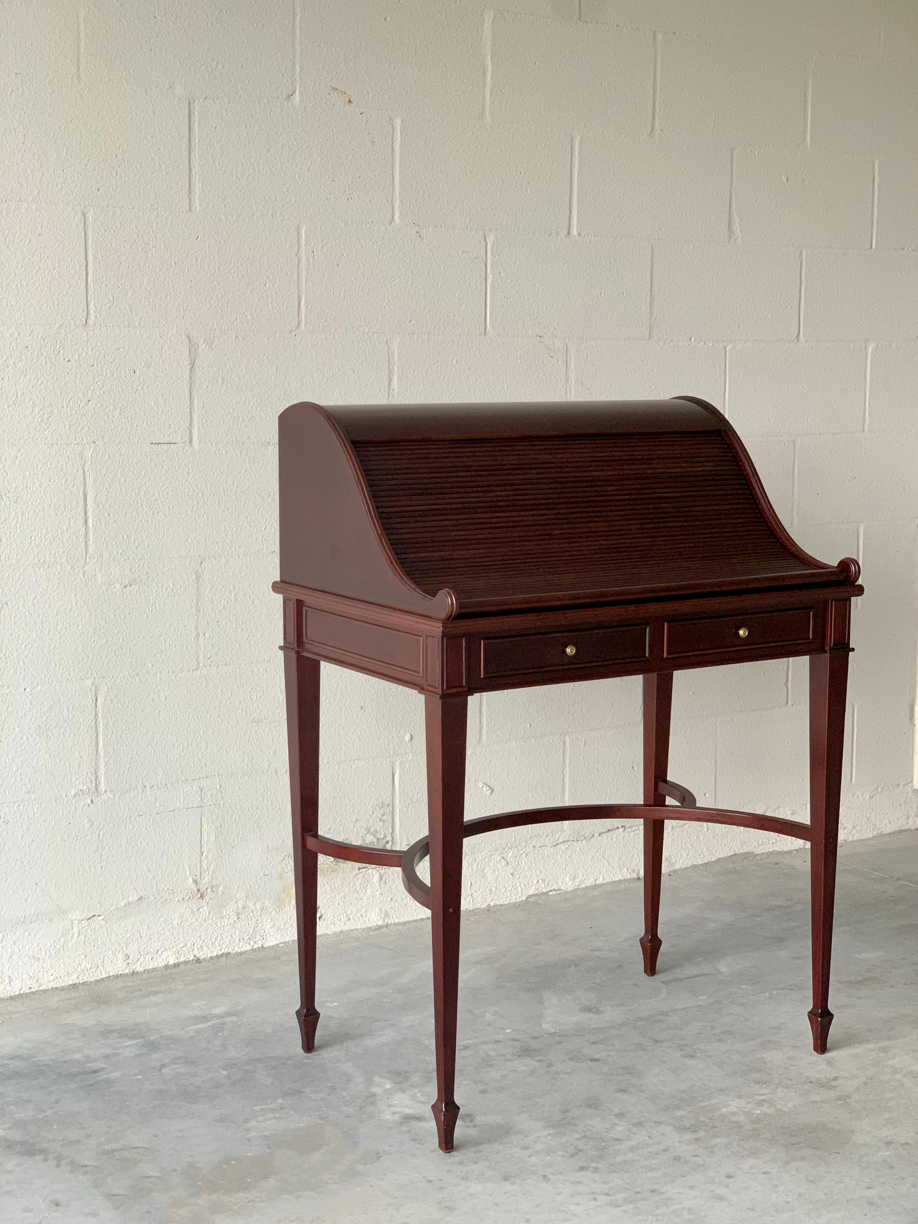 Secretary desk by Bombay Furniture Co. Beautiful veneer mahogany finish. Dated 2004. Table maintains it s sturdy structure, with good wood surface condition despite age. Roll top opens to an inlaid leather writing surface.

DIMENSIONS:
30ʺ Width ×