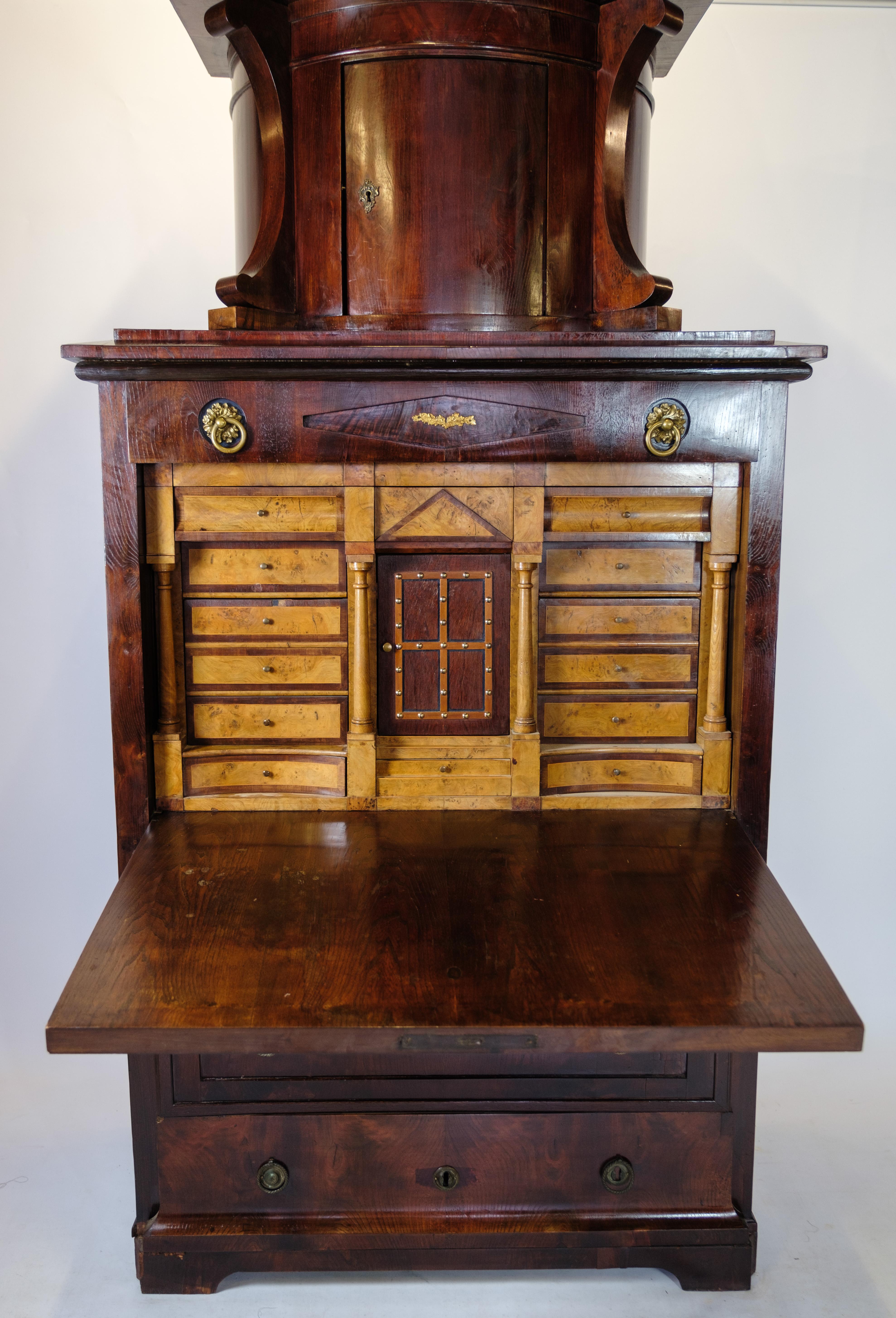 German secretary of patinated elm wood with top and brass fittings decorated with marquetry from Berlin around the 1840s.
Dimensions in cm: H:207.5 W:106 D:50