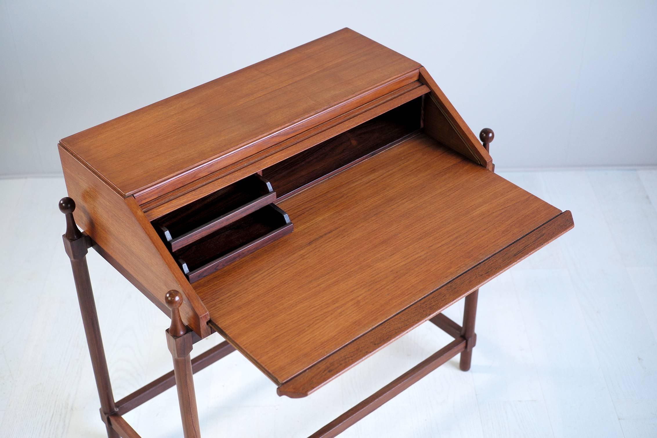 Secretary in teak and rosewood system from Proserpio Fratelli, Italy, 1960. The tablet unfolds revealing the rosewood interior, with two drawers and a housing. Pushing the tray, the curtain comes close the box. The pillar base is in solid
