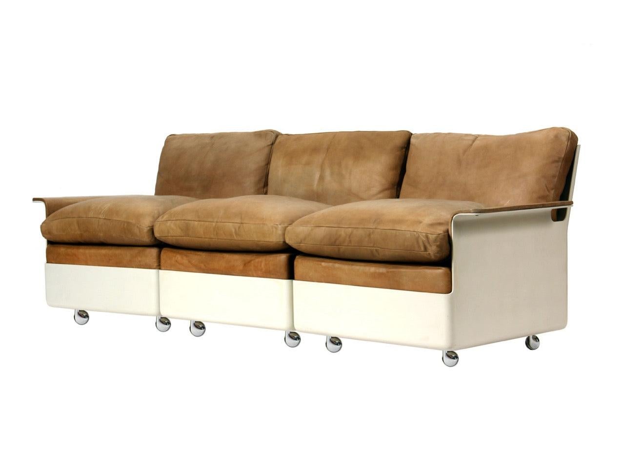 Un canapé sectionnel Gull Wing de trois (3) pièces avec des coussins en cuir naturel fauve dans un cadre en fibre de verre blanc cassé monté sur roulettes. Fauteuil également disponible.