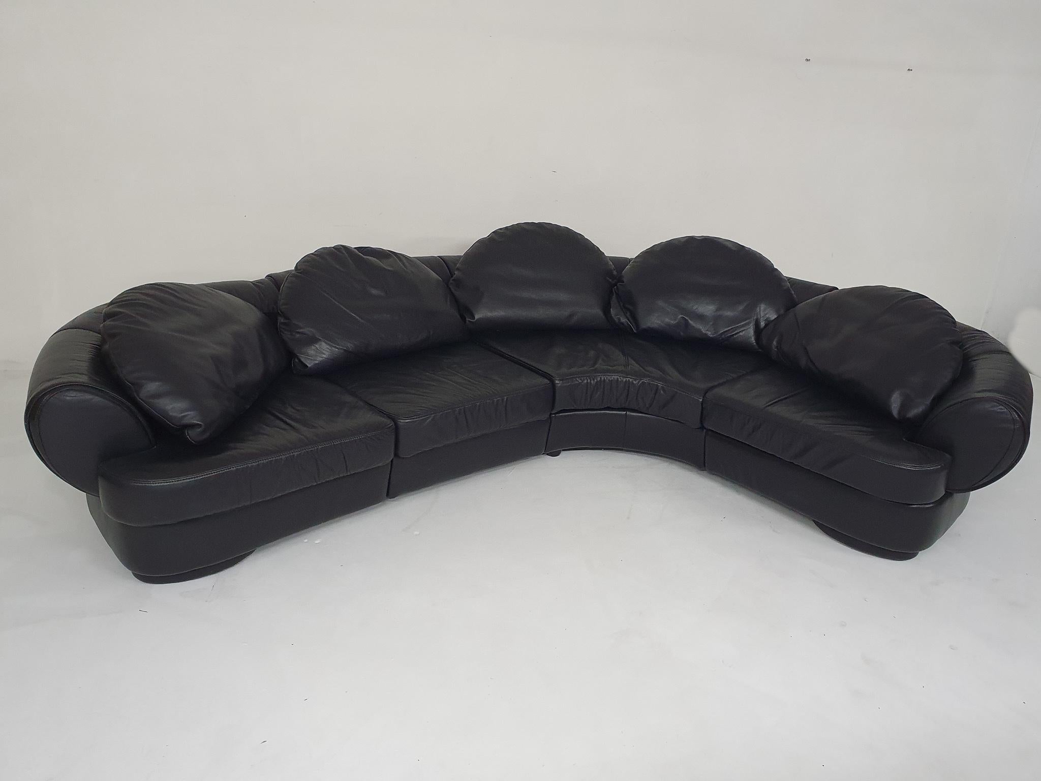 Canapé sectionnel en cuir noir d'origine de haute qualité. Le canapé date des années 80 mais est encore en bon état. Il se compose de 4 parties qui sont fixées l'une à l'autre par des broches métalliques. Les coussins de dos en forme de lune sont