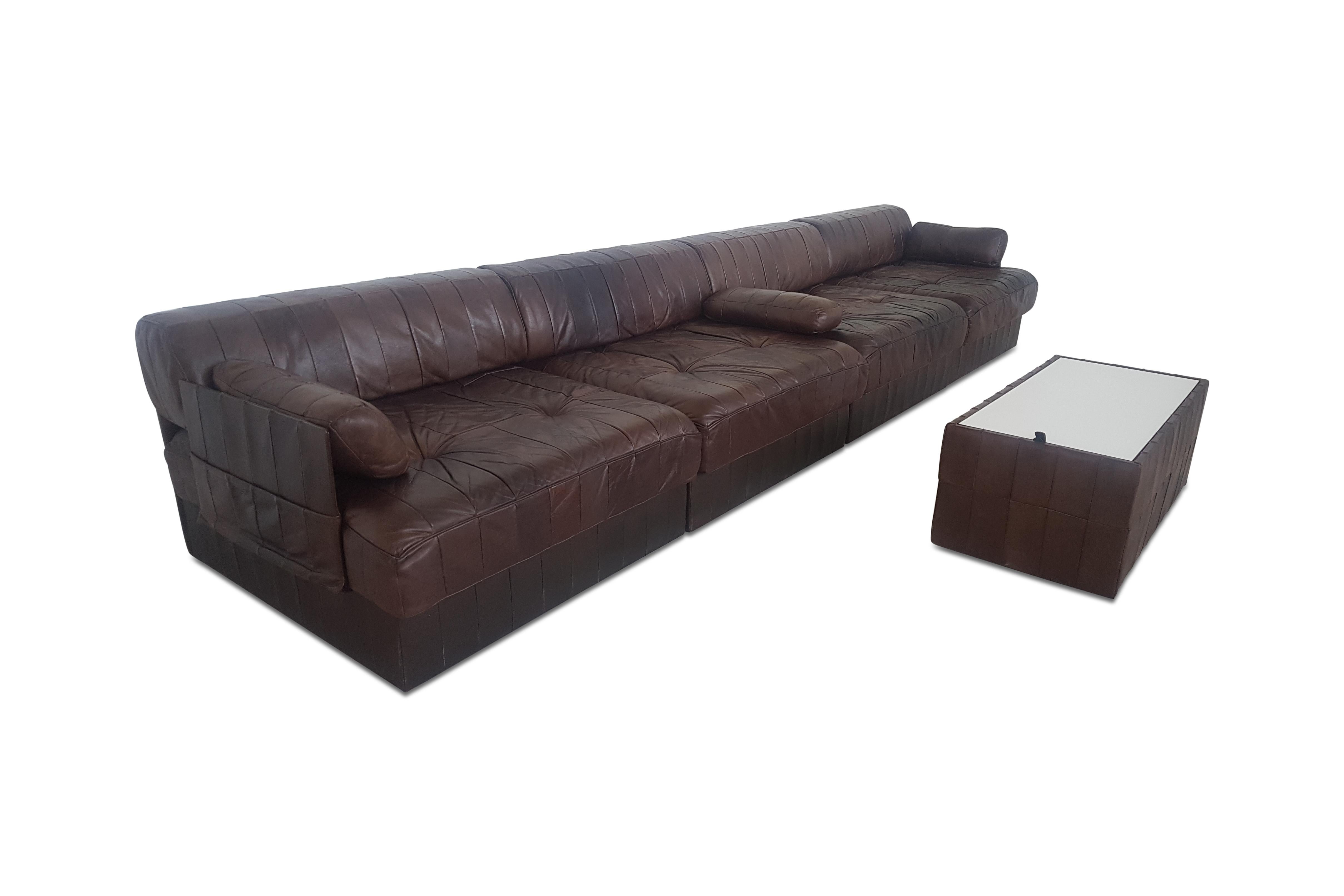 De Sede modular sectional leather sofa in dark brown patch work leather.
The sofa is in four sections, each with a base leather patchwork cushion and a back cushion made from the same soft luxurious leather. A small side table which can also be