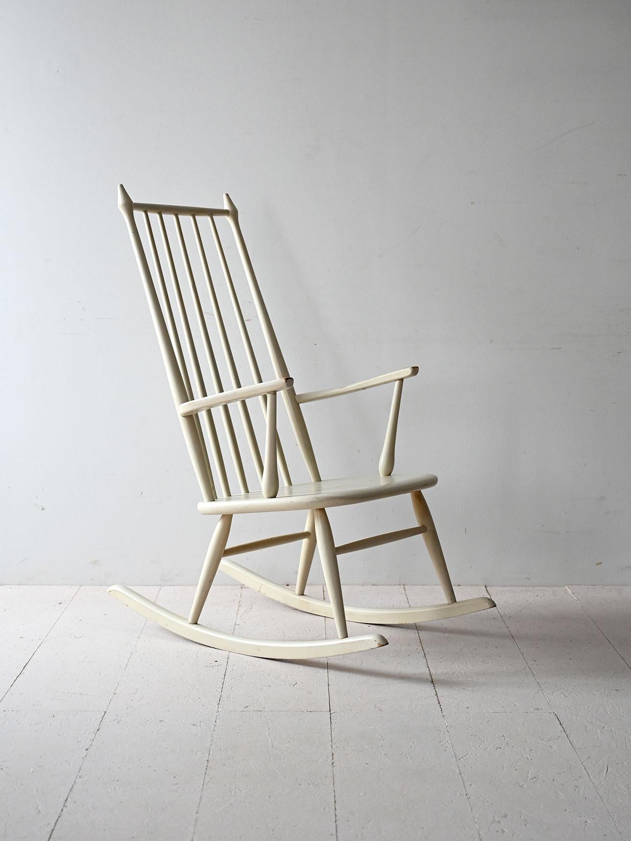 Mecedora escandinava de madera lacada, con respaldo alto de listones y delgados reposabrazos. Estructura ligera y elegante.

Mecedora escandinava de mediados de siglo, de madera lacada. El diseño se caracteriza por un respaldo alto con lamas