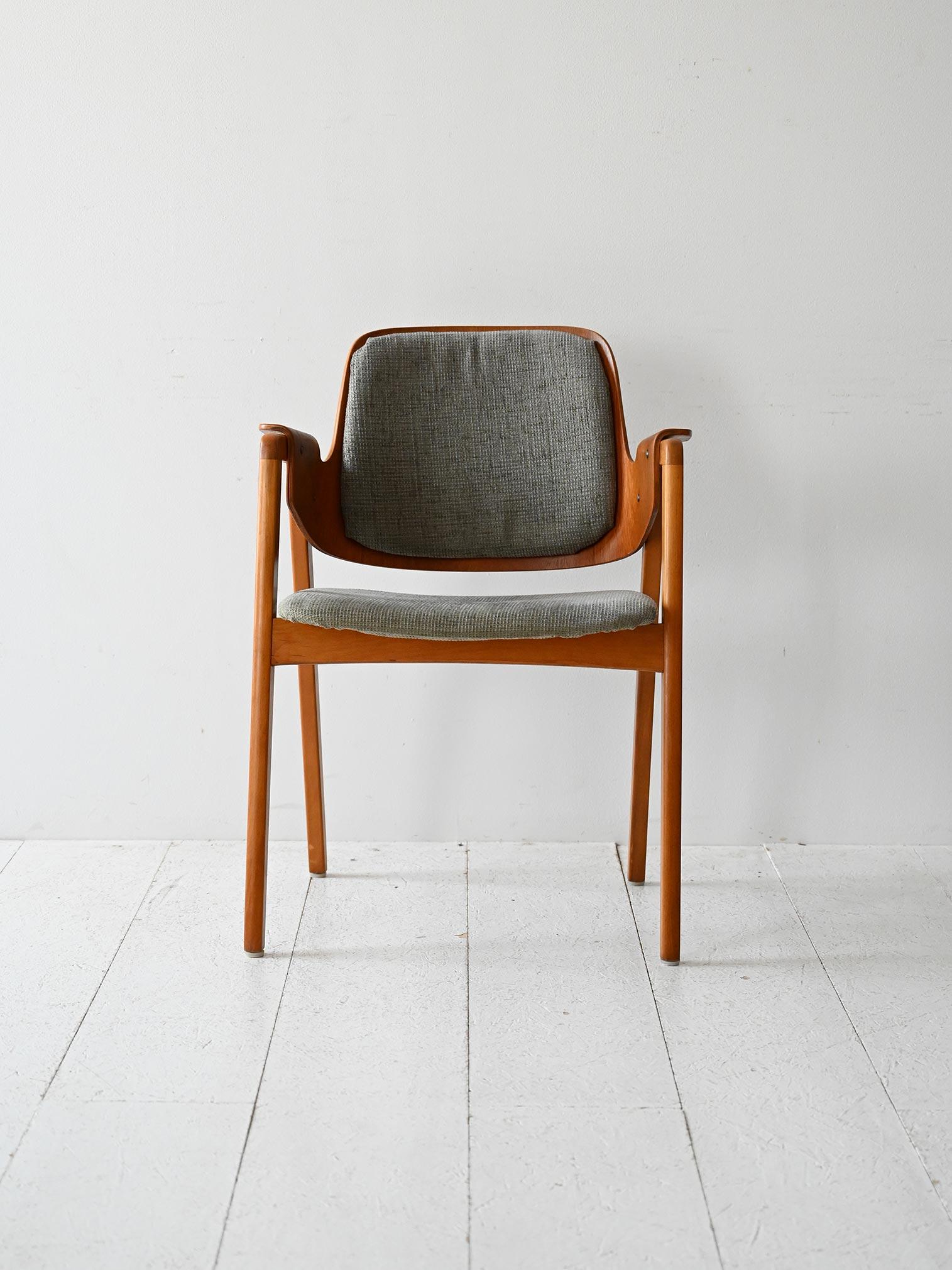 Silla de escritorio de madera con asiento tapizado, reposabrazos tallados, probable producción sueca Gärsnäs años 50/60.

Silla de escritorio escandinava vintage con estructura de madera maciza y funda de tela gris. Los reposabrazos perfilados y el
