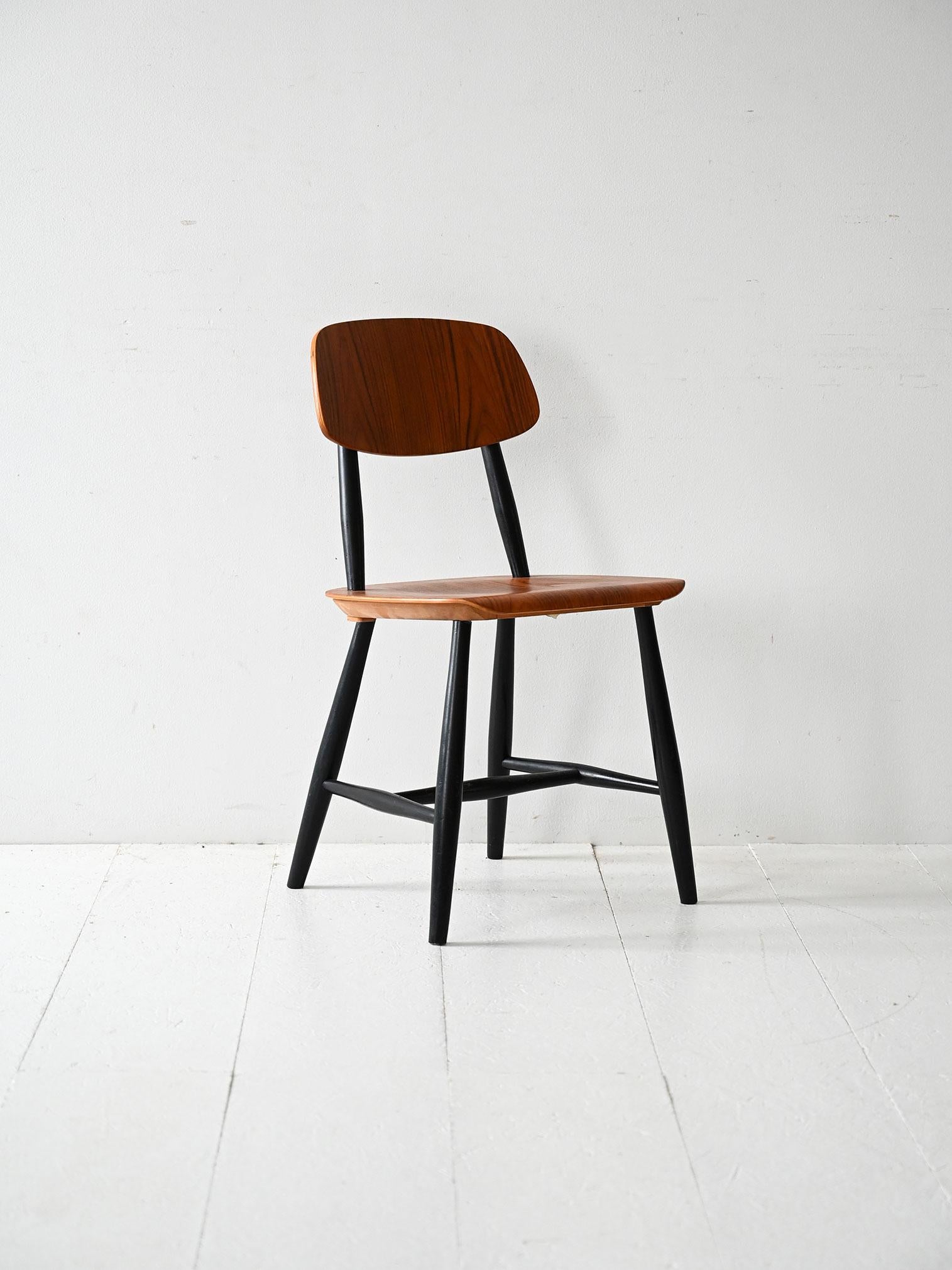 Chaise scandinave vintage avec structure laquée noire et assise en teck. Un design élégant qui met en valeur le contraste entre les matériaux.

Chaise scandinave vintage avec un cadre laqué noir et une assise et un dossier en teck avec un beau grain