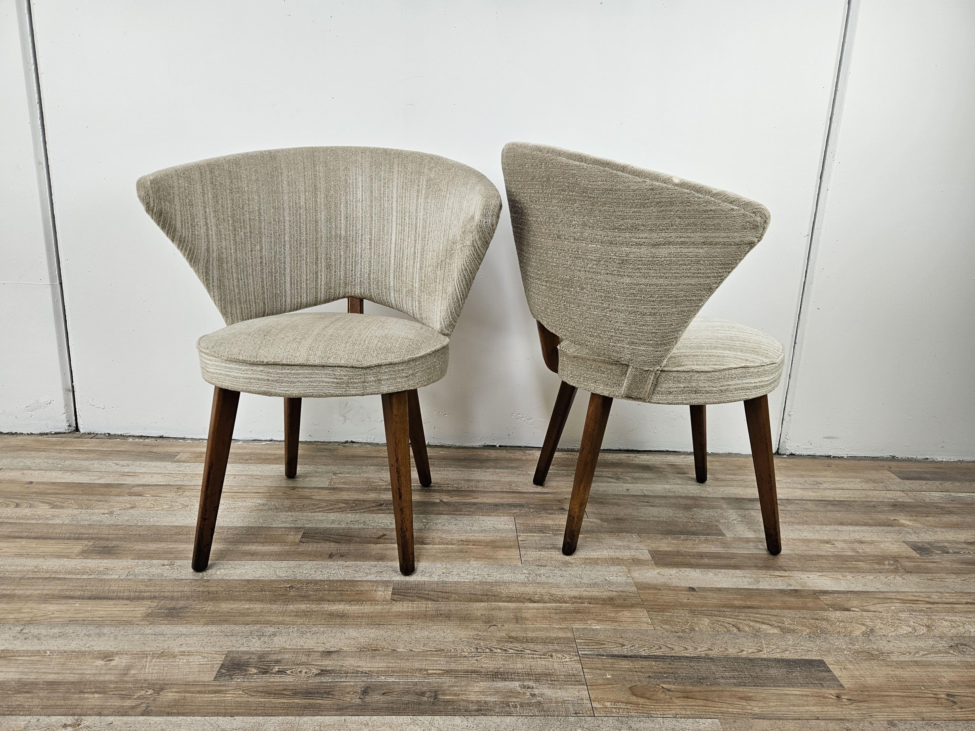 Coppia di poltroncine da cocktail per soggiorni o zone bar, molto particolare con quattro gambe alte in legno e struttura rivestita in stoffa grigio/beige.

Sotto la seduta riportano un'etichetta tedesca di Hannover.

Il tessuto è originale