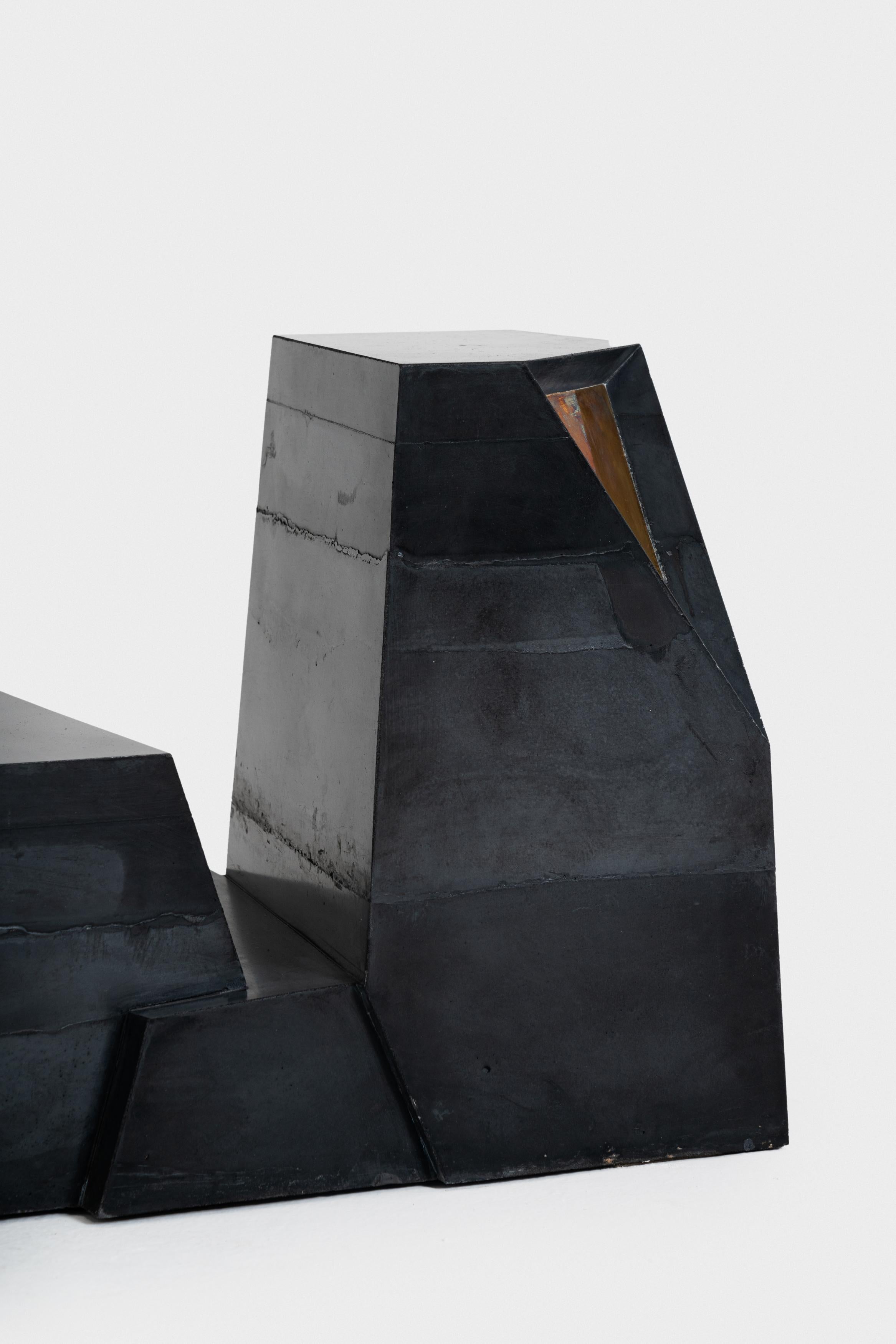 Die Betonblöcke stellen sich zwischen die Möbel und die architektonischen Elemente. Die Linien, die durch die Gießtechnik auf der Oberfläche hinterlassen werden, sind dann Schatten der Umgebung. Polierte Messingeinsätze spielen ebenfalls mit dem