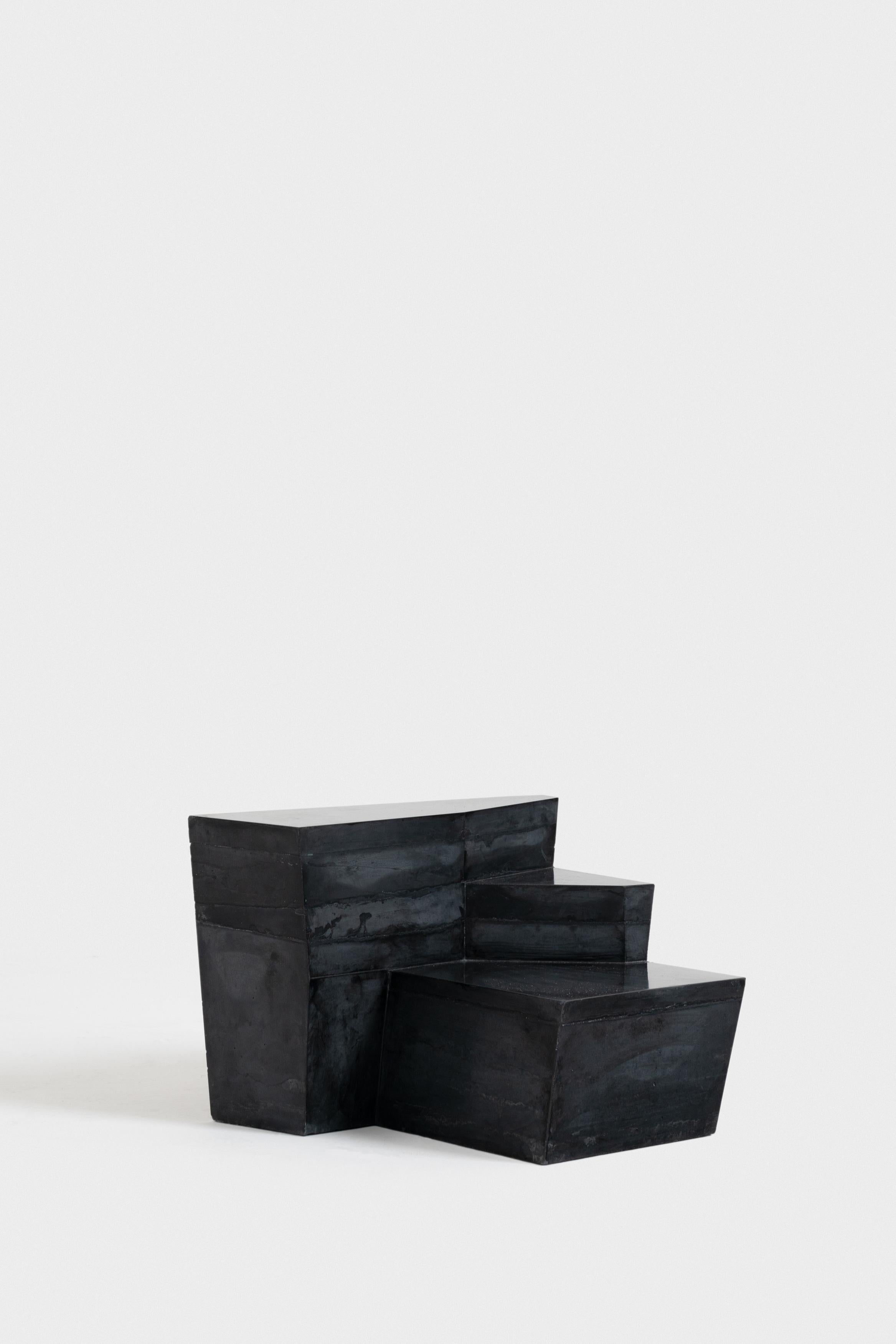 The concrete blocks place themselves in between furniture and the architectural elements. Lines left on the surface by the pouring technic are then shadows of the surrounding. Polished brass inserts also play with light and with both the surrounding