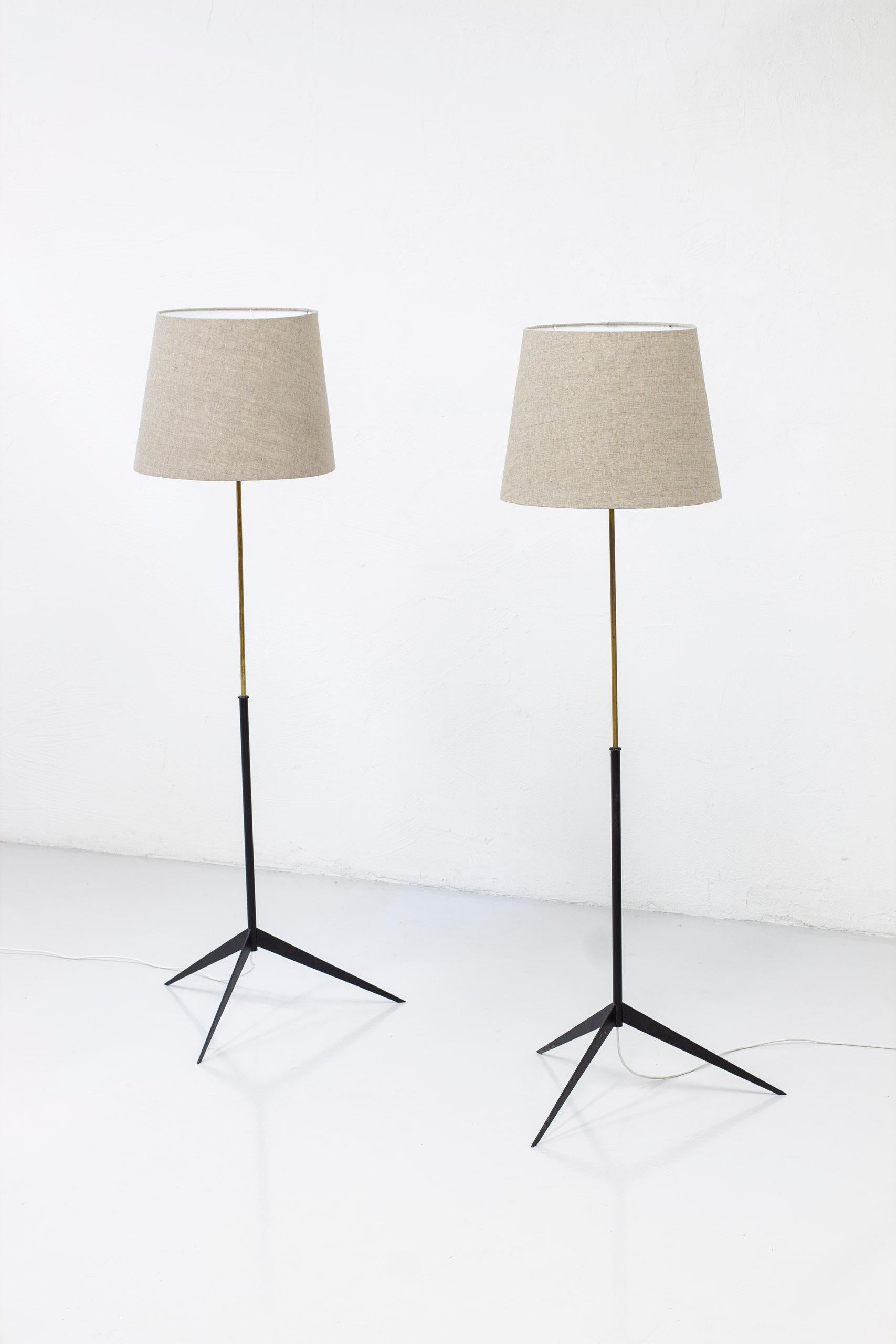 Pair of floor lamps model G-30R designed by Alf Svensson. Produced in Sweden by Bergboms during the 1950s. Made from black lacquered metall and polished brass. Lamp shades in Natural/grey linnen fabric. Light switch on both lamp holders in working