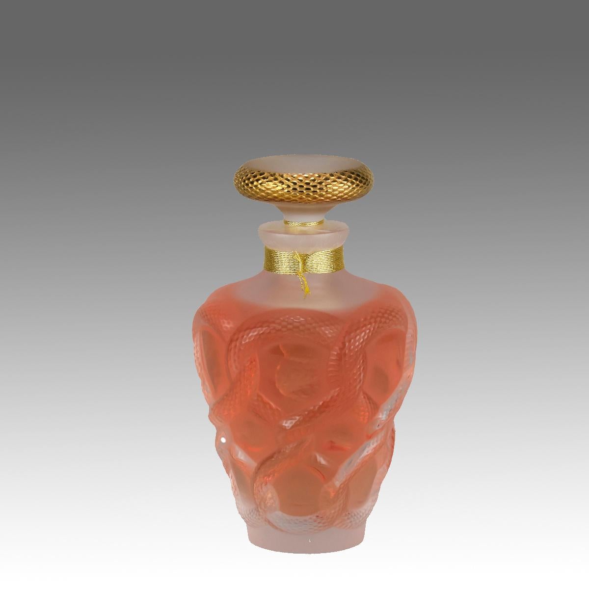 Un flacon de parfum en édition limitée en verre clair et givré, le corps en verre clair contenant le parfum original Lalique décoré de plusieurs corps de serpents en relief entrelacés ensemble autour de la circonférence avec de fins détails, signé