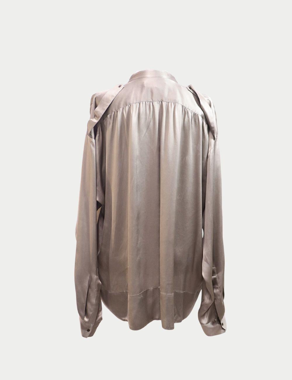 Eleva il tuo guardaroba con questa blusa in seta color kaki di See by Chloé, una lussuosa interpretazione dello stile chic senza sforzo. Realizzata in seta fluida, questa blusa presenta una silhouette oversize con un drappeggio moderno, tasche