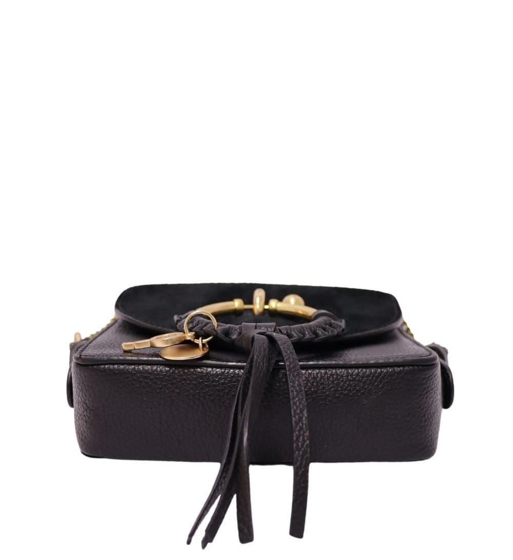 Add boho-chic flair to your accessories edit with this See by Chloé black leather crossbody bag. Designed with a structured mini silhouette, this bag features the brand’s signature gold-tone ring with braided leather and playful charms on the front