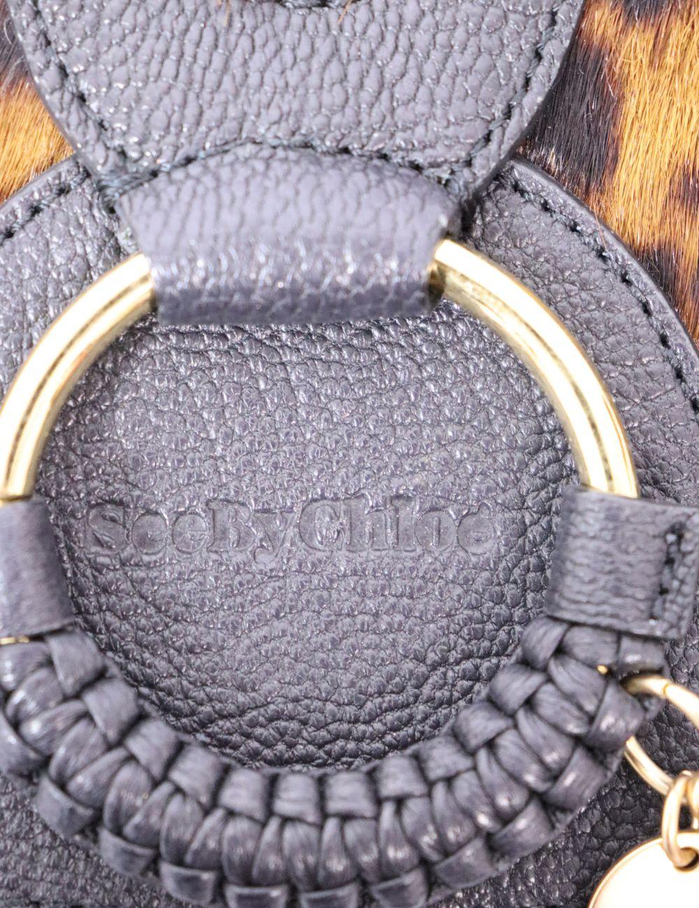 La audacia se une al estilo boho en este llamativo bolso cruzado See by Chloé. Confeccionada en lujosa piel negra granulada y acentuada con paneles de pelo de becerro con estampado de leopardo, esta pieza única irradia una sofisticación juguetona.