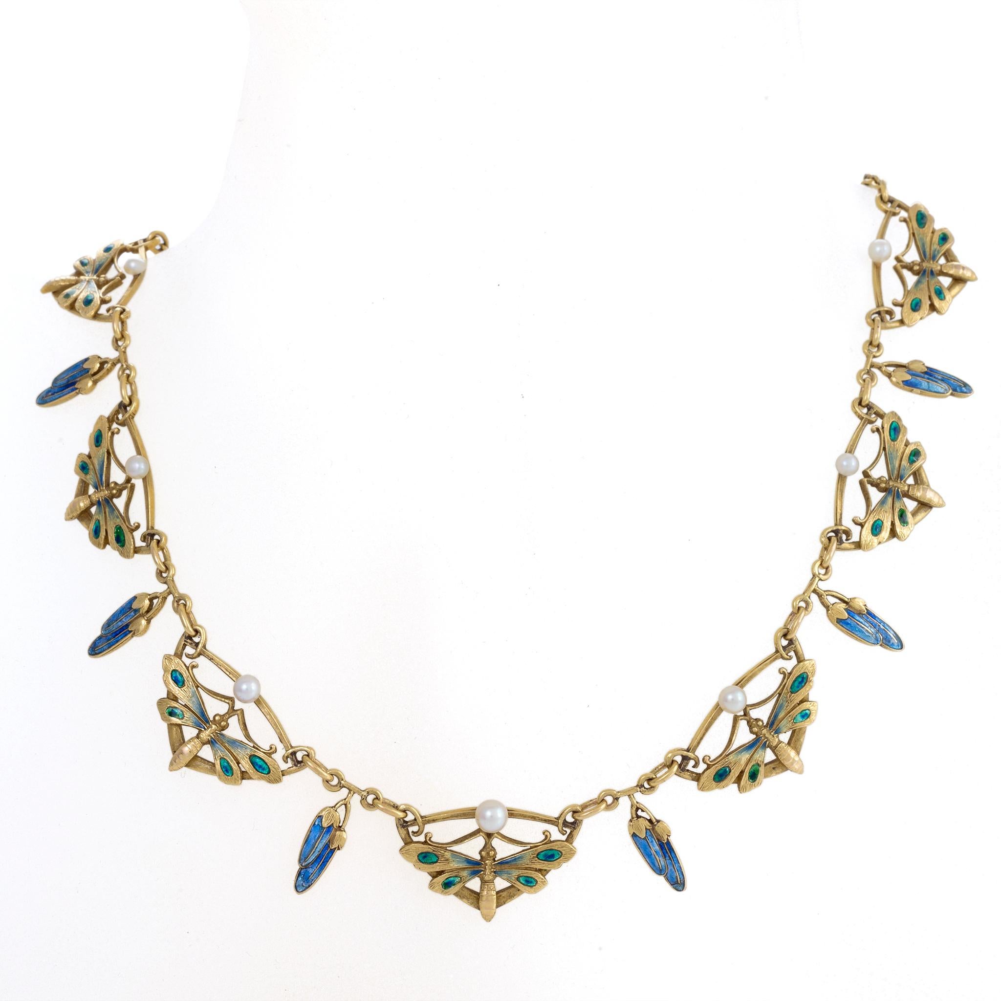 Created around 1900, this Art Nouveau necklace is composed of gold, enamel, and seed pearls. With chased and engraved gold surfaces, the seven green and blue enamel butterflies are interspersed with double blue enamel pendant flower buds and