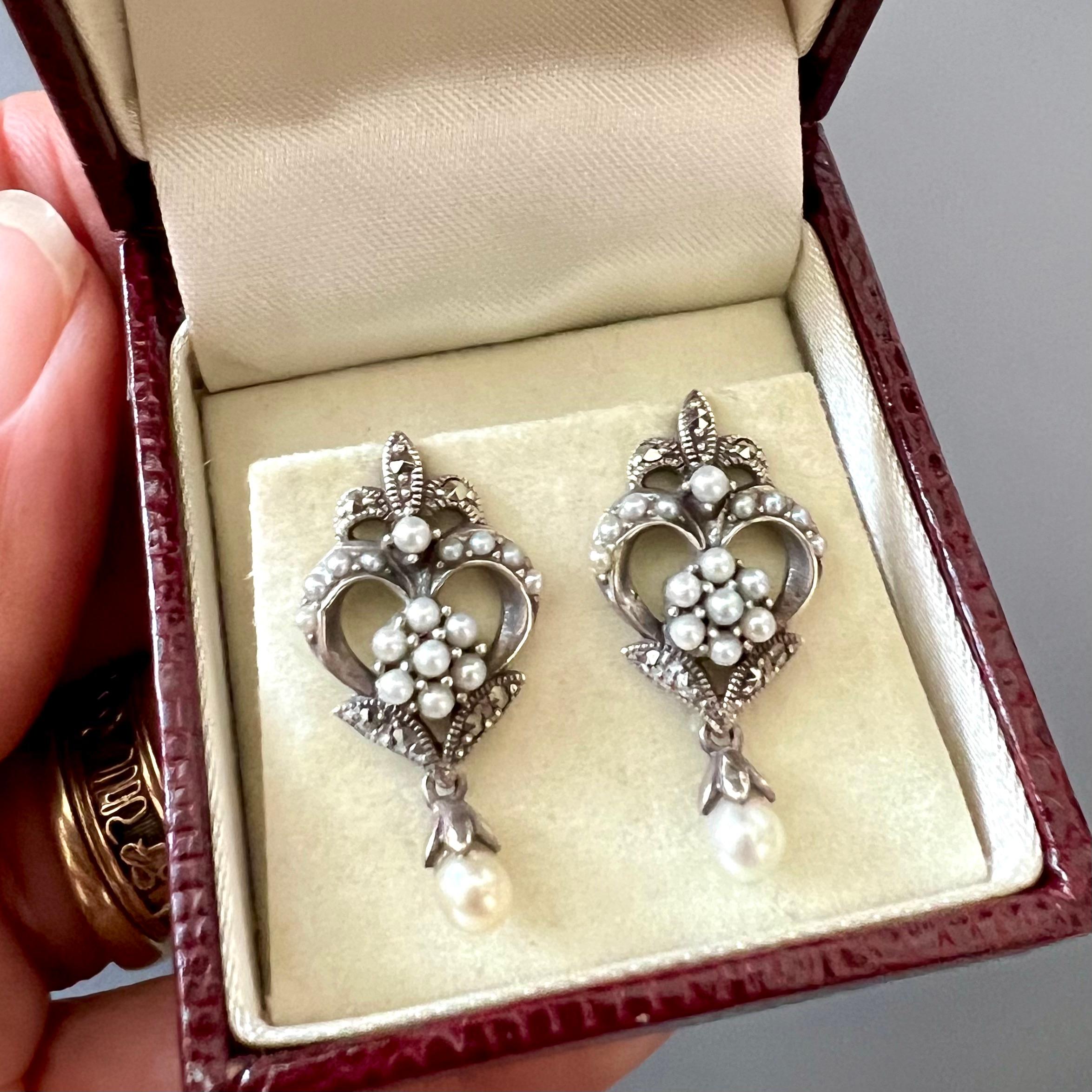 This exquisite pair of cultured seed pearl and marcasite earrings showcases a timeless design crafted from sterling silver. At the top of the earrings, the fleur-de-lis symbol is beautifully displayed, intricately detailed with marcasite stones that