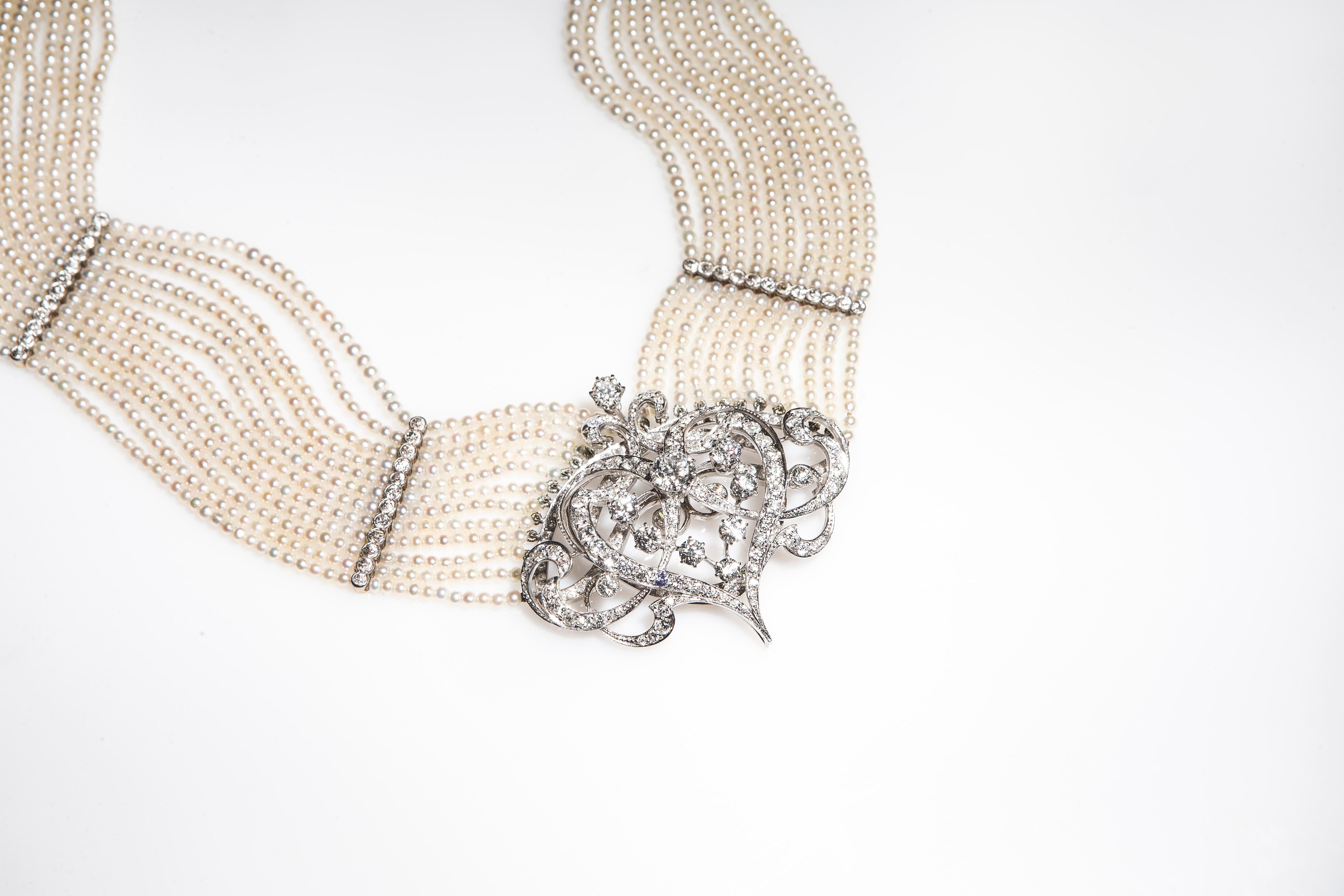 Stunning choker composed of 12 strands of seed pearls (circa 2,5 mm to 3 mm) well matched, of cream body color with faint rose overtones. They are of good quality and luster. 
The strands are divided by finely wrought partitions made of platinum and