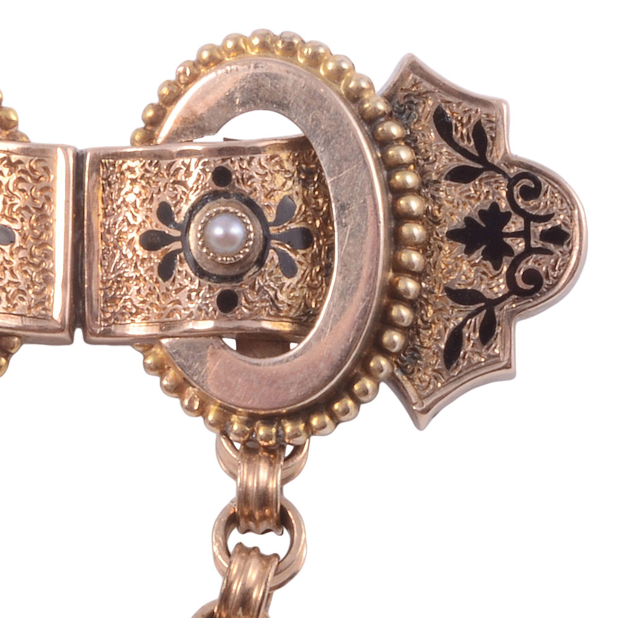 Antique seed pearl enamel pin, circa 1920. This antique pin is crafted in 10 karat yellow gold and features enameling and two seed pearls. This pin has an attached loop chain. [ADTI AOT1765]

Dimensions
1.4″H x 1.5″W