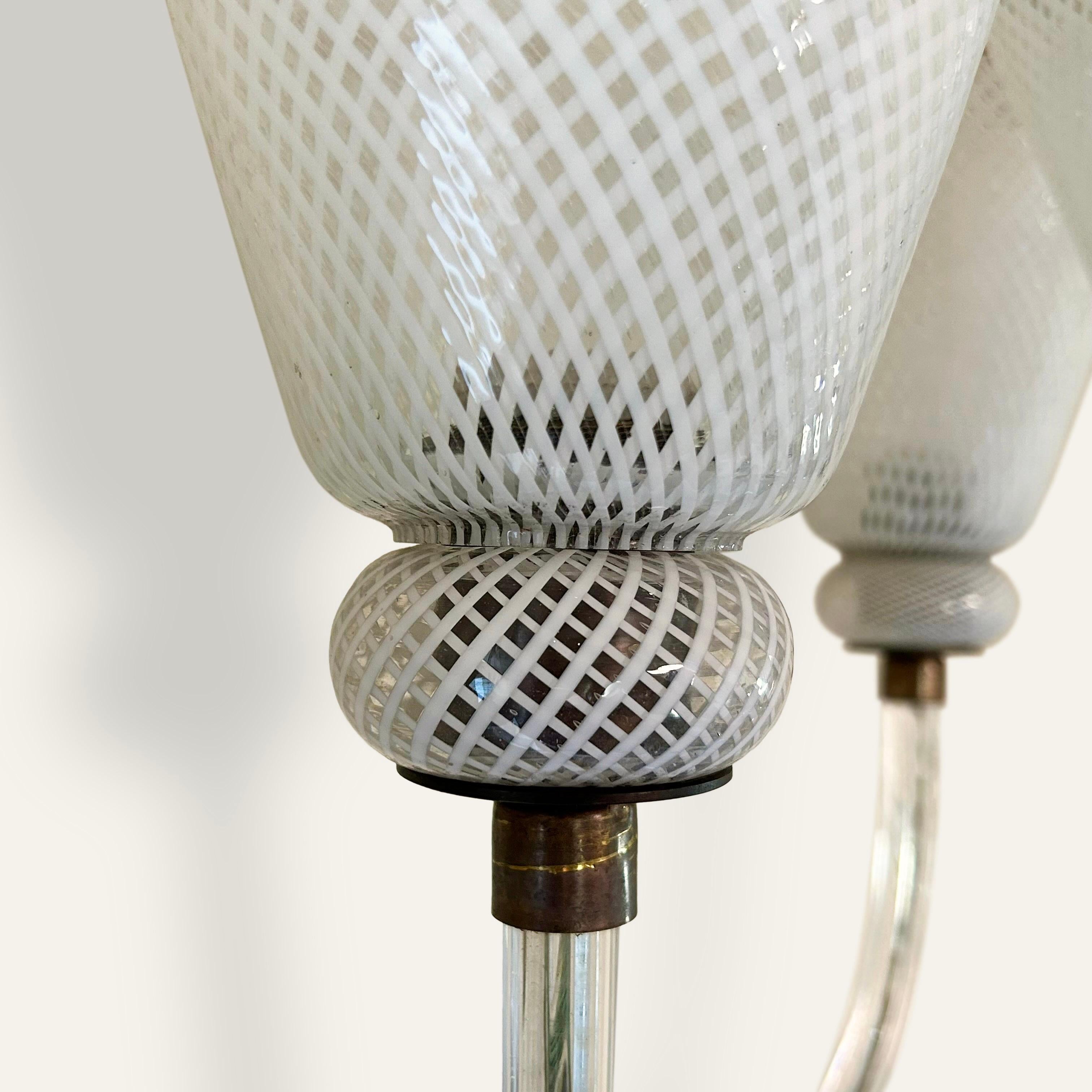A pair of 1940s Italian Seguso wall lights. Each light with hand blown arms and conical shades executed in the Reticello technique, finished with brass ribbed hardware. 

