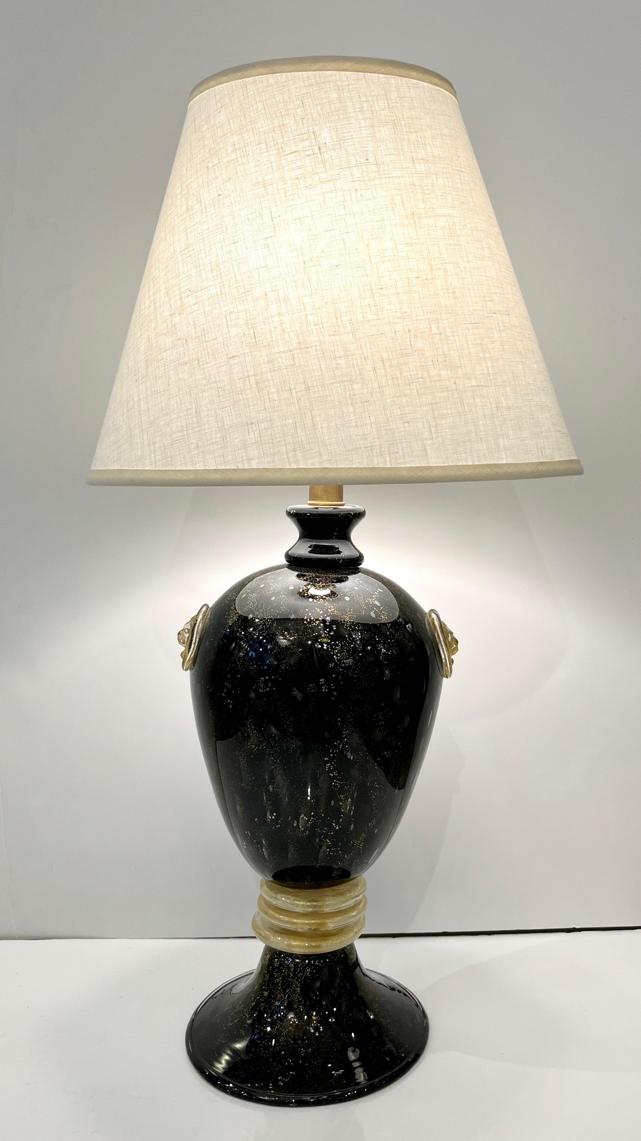 A pair of very elegant lamps attributed to Archimede Seguso, high quality of execution with Grand Tour design, the delicately curved bodies in blown black Murano glass decorated with the head of the Lion of Venice in an escutcheon in relief on each