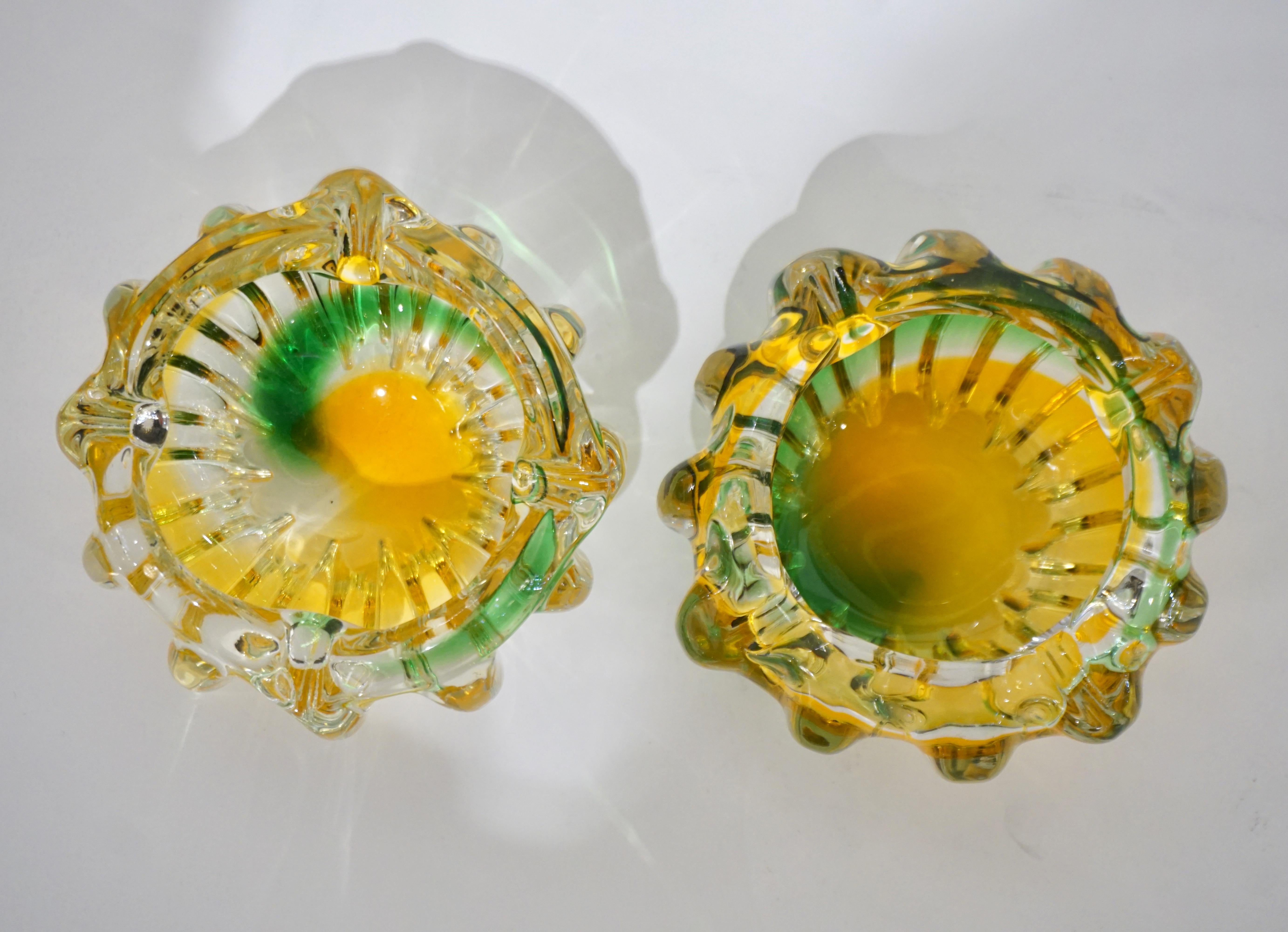 An antique Italian pair of Art Deco small flower shape cups attributed to Archimede Seguso, in blown reeded Murano glass accented by pinched scalloped edges, the crystal clear Murano glass decorated with emerald green and amber gold swirls.
Ideal