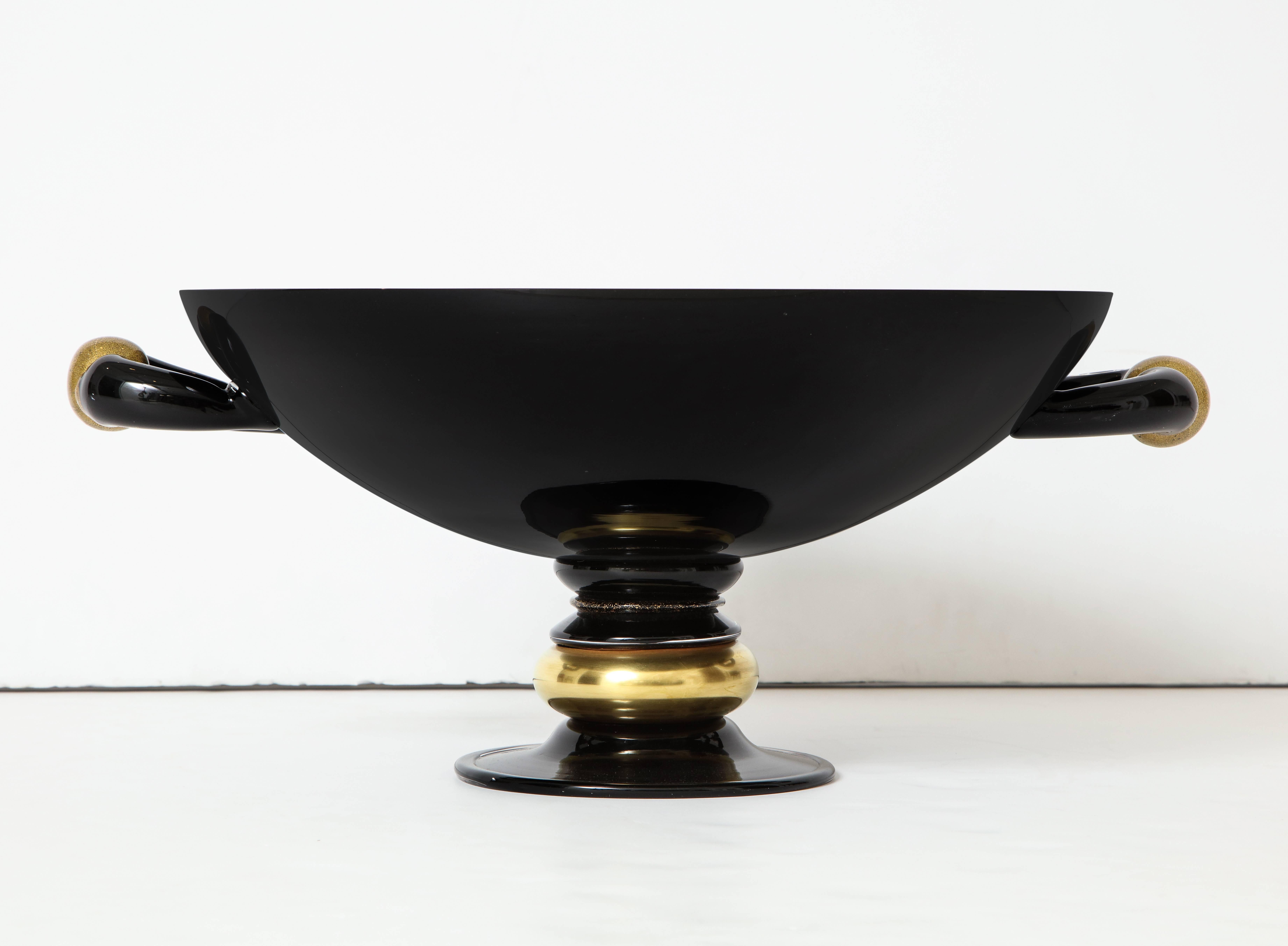 Large centrepiece bowl with a segmented base and applied handles and a neoclassical mien. Black with gold accents. Made by Seguso for Loren Marsh, circa 1989. According to a Seguso executive, the applied handles, with their gold-flecked circular