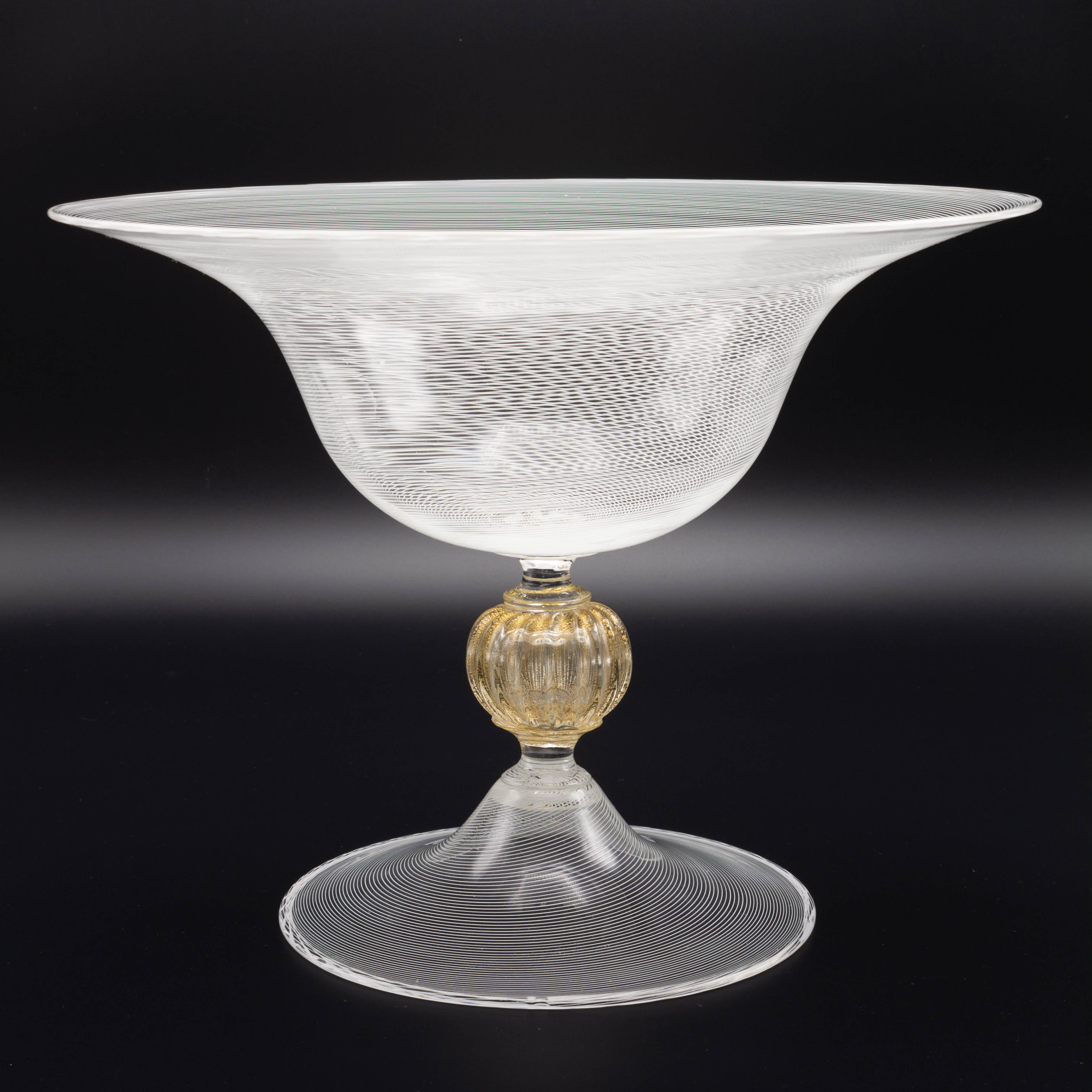A mid century Murano glass footed centerpiece bowl or tazza attributed to Seguso. This large bowl features fine linear filigree with center gold flecked ribbed knob stem and flared foot base. Measures: 9