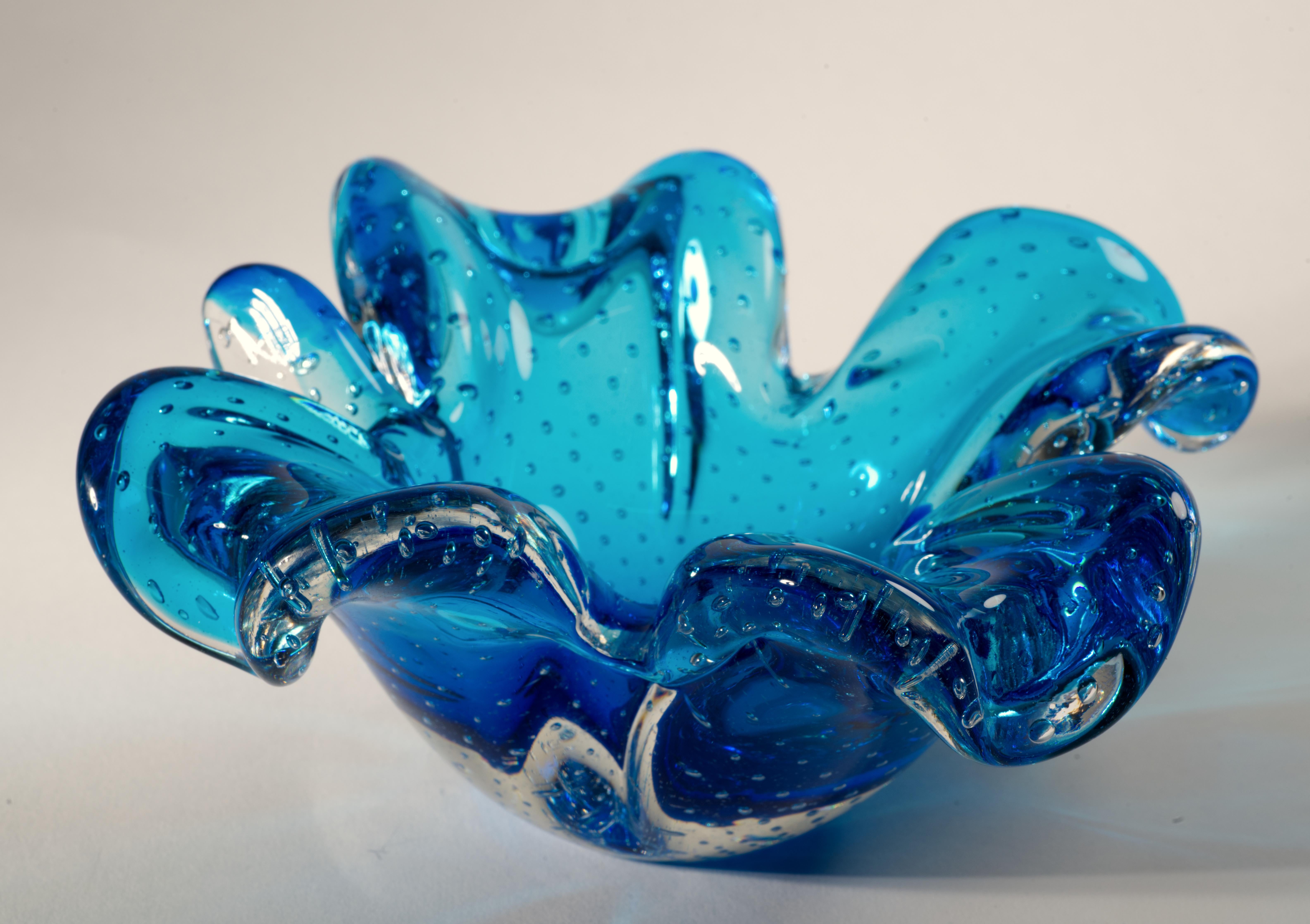  Pesado y escultural cuenco de cristal de Murano fabricado en cristal azul con efecto de burbujas controladas encerrado dentro de la capa de cristal transparente en técnica sommerso. Tiene forma de trébol de cuatro hojas; la parte de cristal
