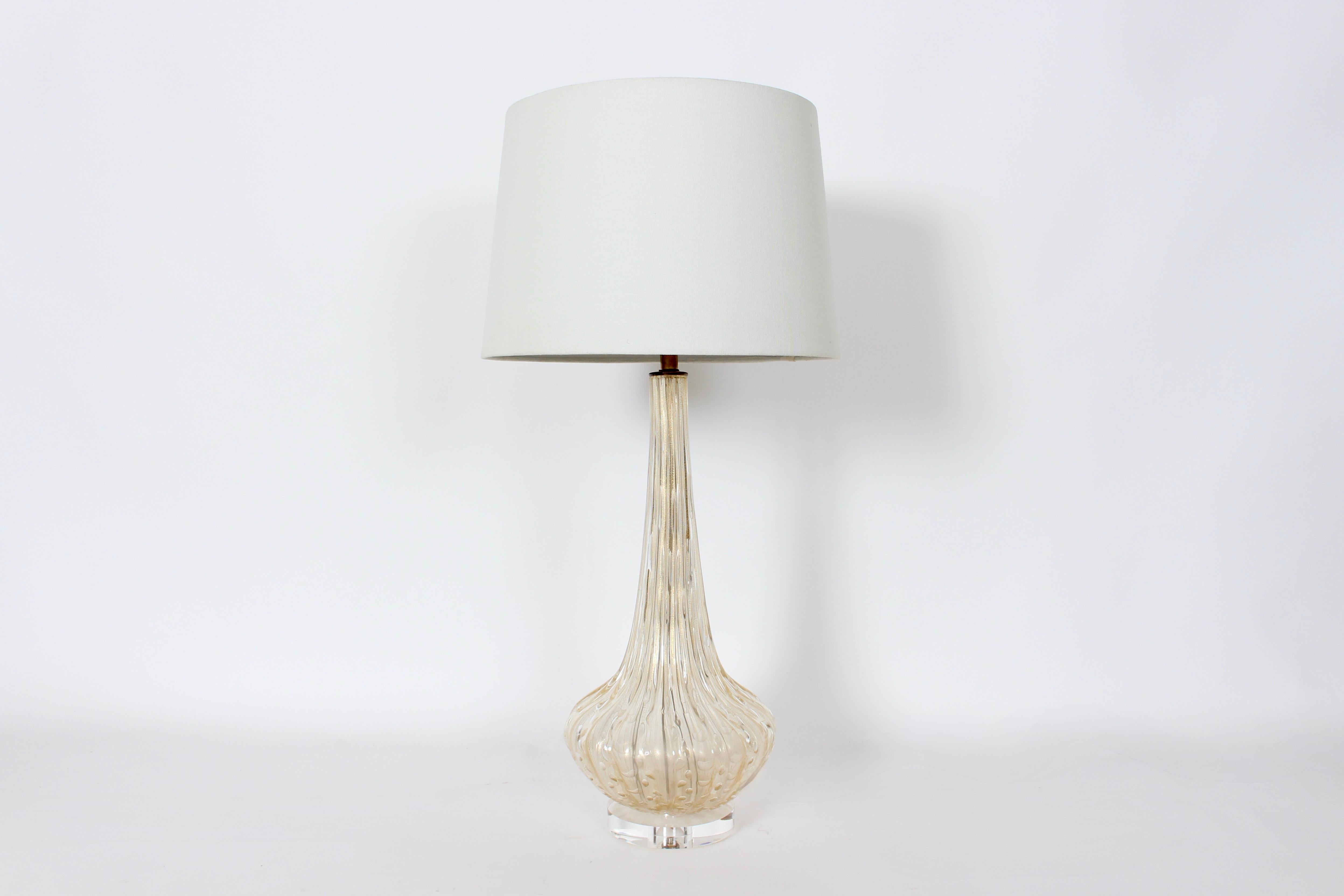 Lampe de table italienne du milieu du siècle en verre Murano Seguso transparent avec des mouchetures d'or.  Le verre soufflé à la main est lisse et nervuré, avec des bulles ovales et des reflets irisés dorés, sur une base en Lucite transparente de