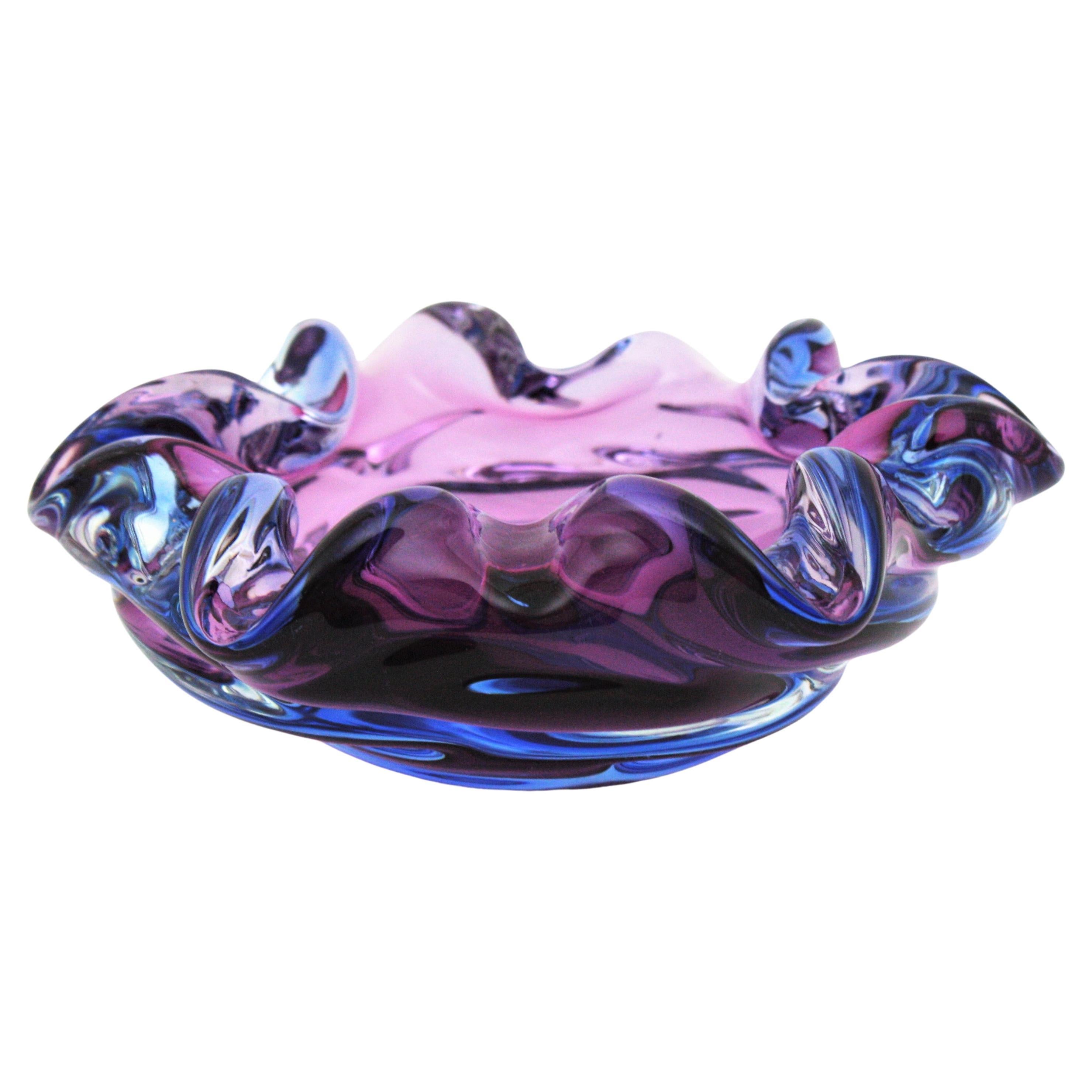 Auffällige Schale aus mundgeblasenem Murano Art Glas in lila, rosa und blauen Farbtönen. Zuschreibung an Seguso, Italien, 1960er Jahre.
Diese schöne Schale besteht aus violettblauem Glas, das mit Sommerso-Technik in Klarglas eingefasst ist. Es hat