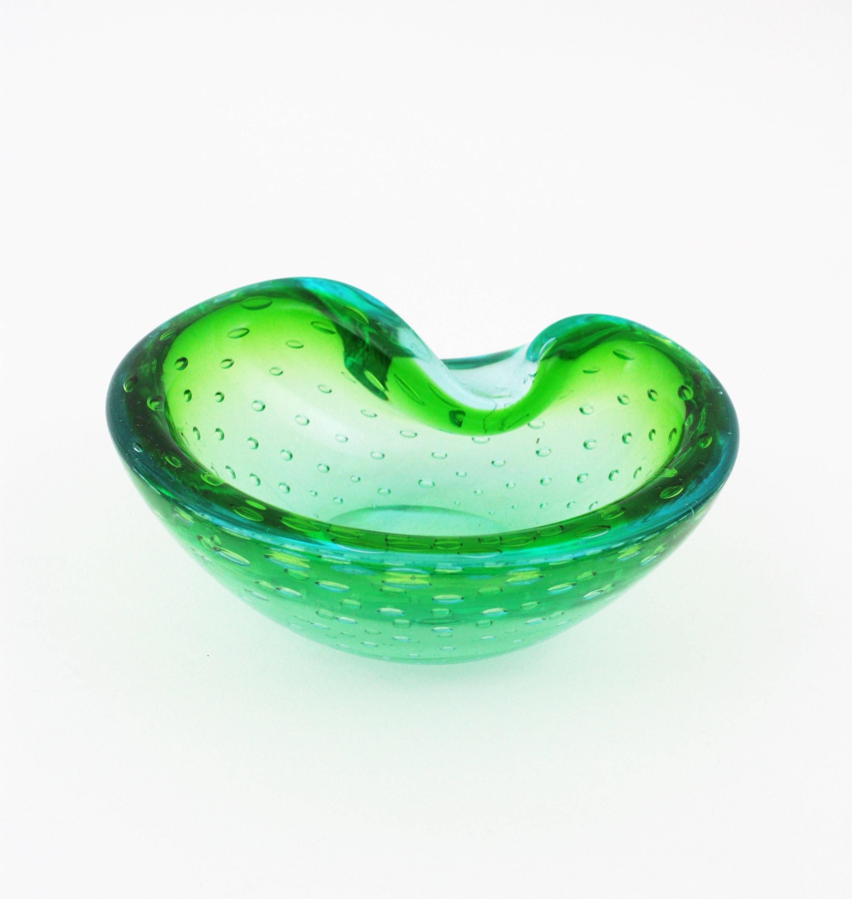 Organic shaped Murano glass bowl or ashtray in lime green and blue with controlled air bubbles. Italy, 1960s.
This art glass hand blown Murano bowl has shades of lime green and turquoise blue edge and hundreds of controlled bubbles.
Attributed to