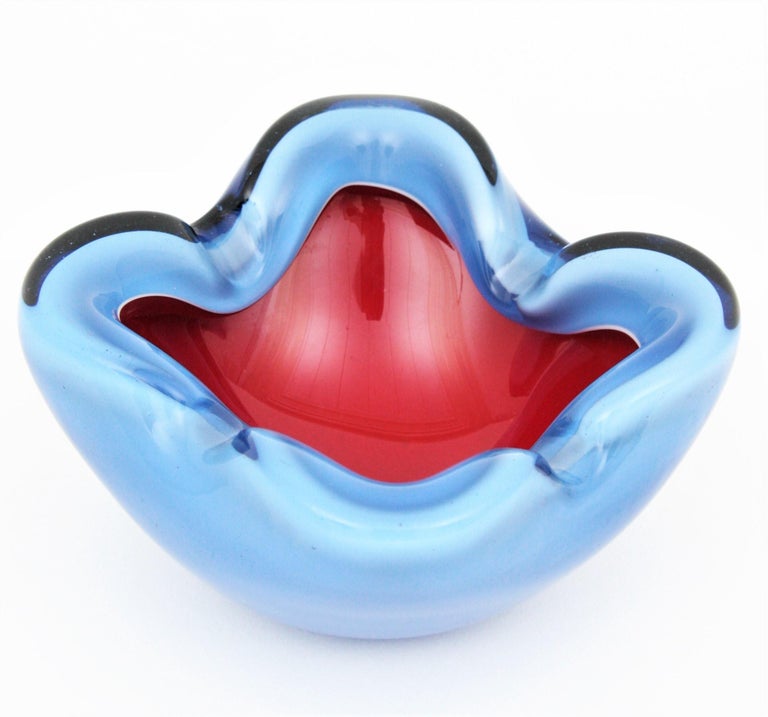 Eye-catching hand blown Opaline sky blue and red Murano glass bowl or ashtray attributed to Seguso, Italy, 1950-1960s.
Sky blue, red and white Opaline glass cased into clear blue glass with highly decorative shapes. An spectacular piece to combine