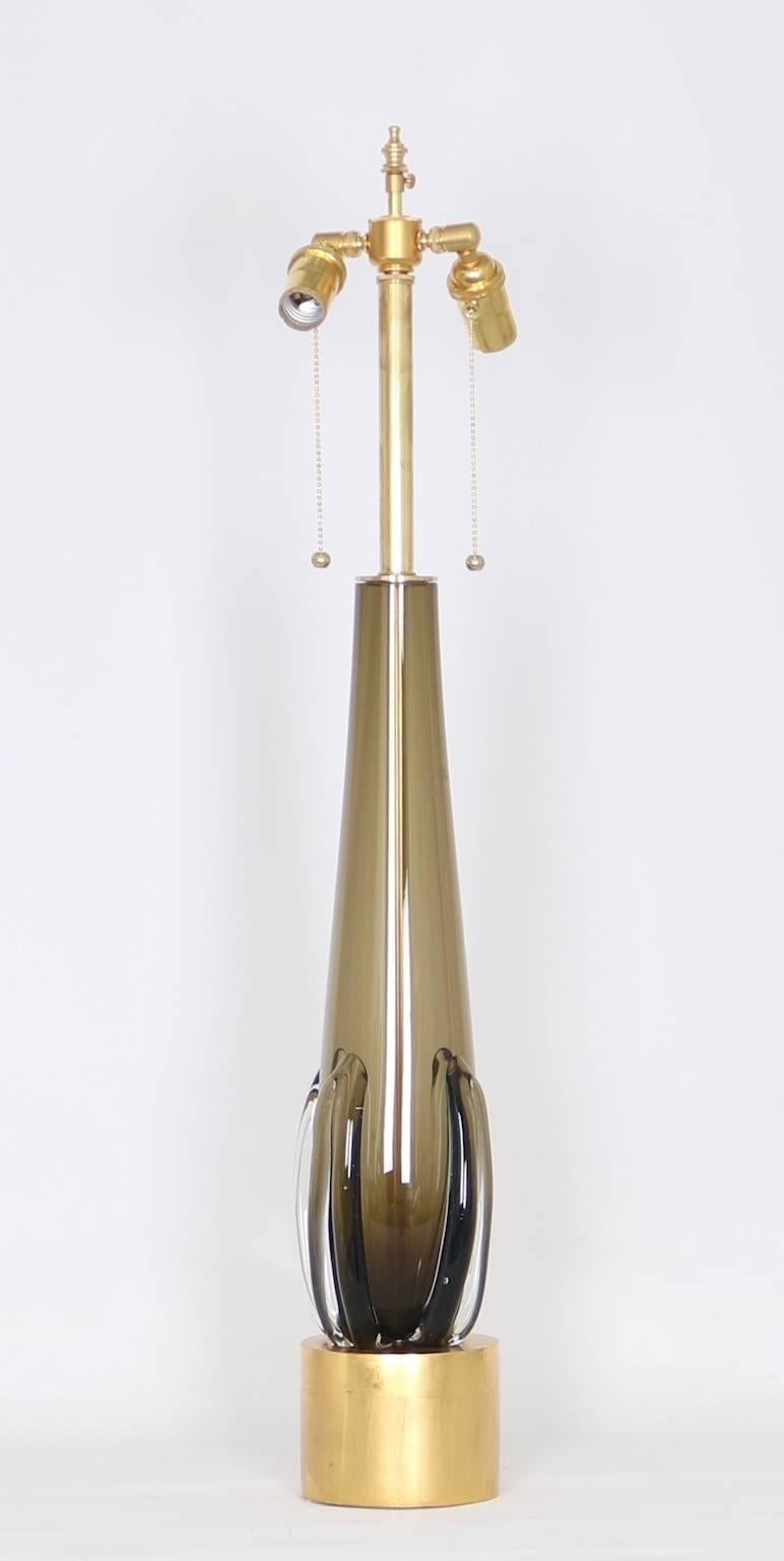 Seguso Mid-Century Modern lamp in Murano Glass. Features a tall smoked glass body mounted on a round gilt wooden base. The glass body is decorated with curved clear glass panels on the bottom. Fully restored with all new wiring and hardware