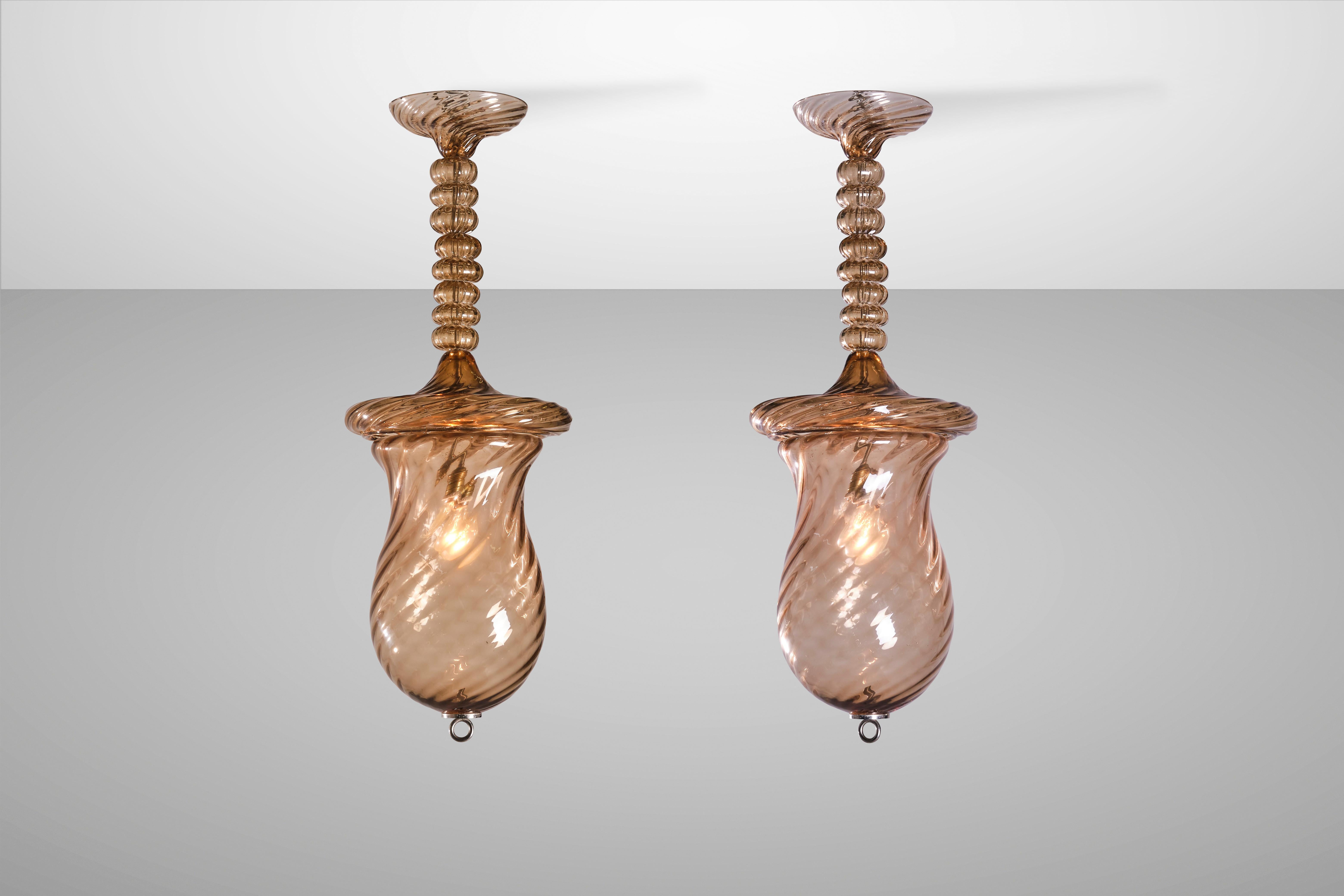 Un'illuminazione che riesce a essere decorativa e funzionale allo stesso tempo è un classico che diventa tale nel tempo. Questi pendenti a coppa color ambra in vetro soffiato Rigadin ritorto sono di una bellezza senza tempo e portano con sé il