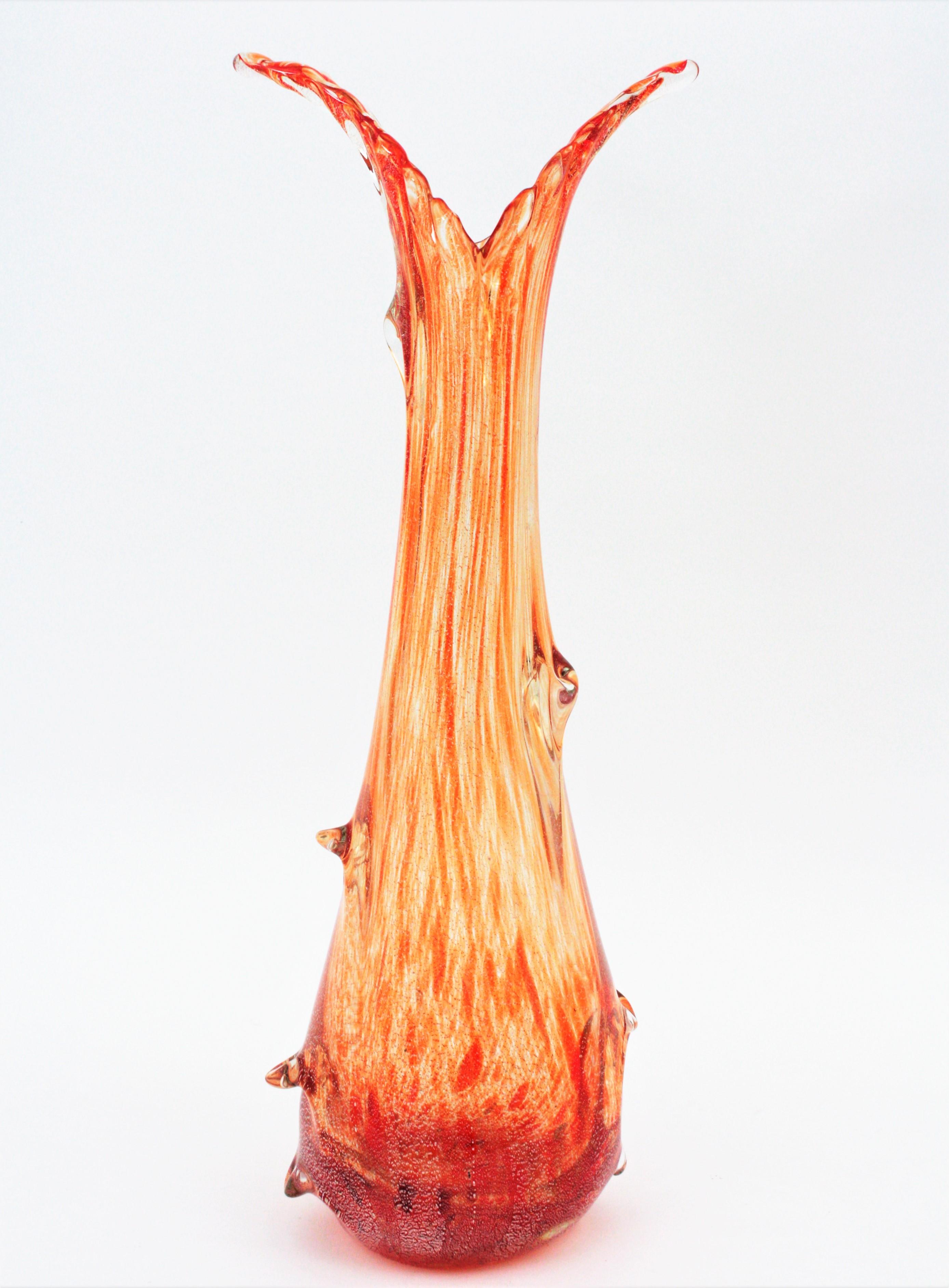 Outstanding hand blown Murano glass vase attributed to Seguso Vetri d´Arte with a beautiful decoration with orange stripes cased in clear glass and silver aventurine flecks. Murano, circa 1940.
The exterior part has large pulled glass decorations