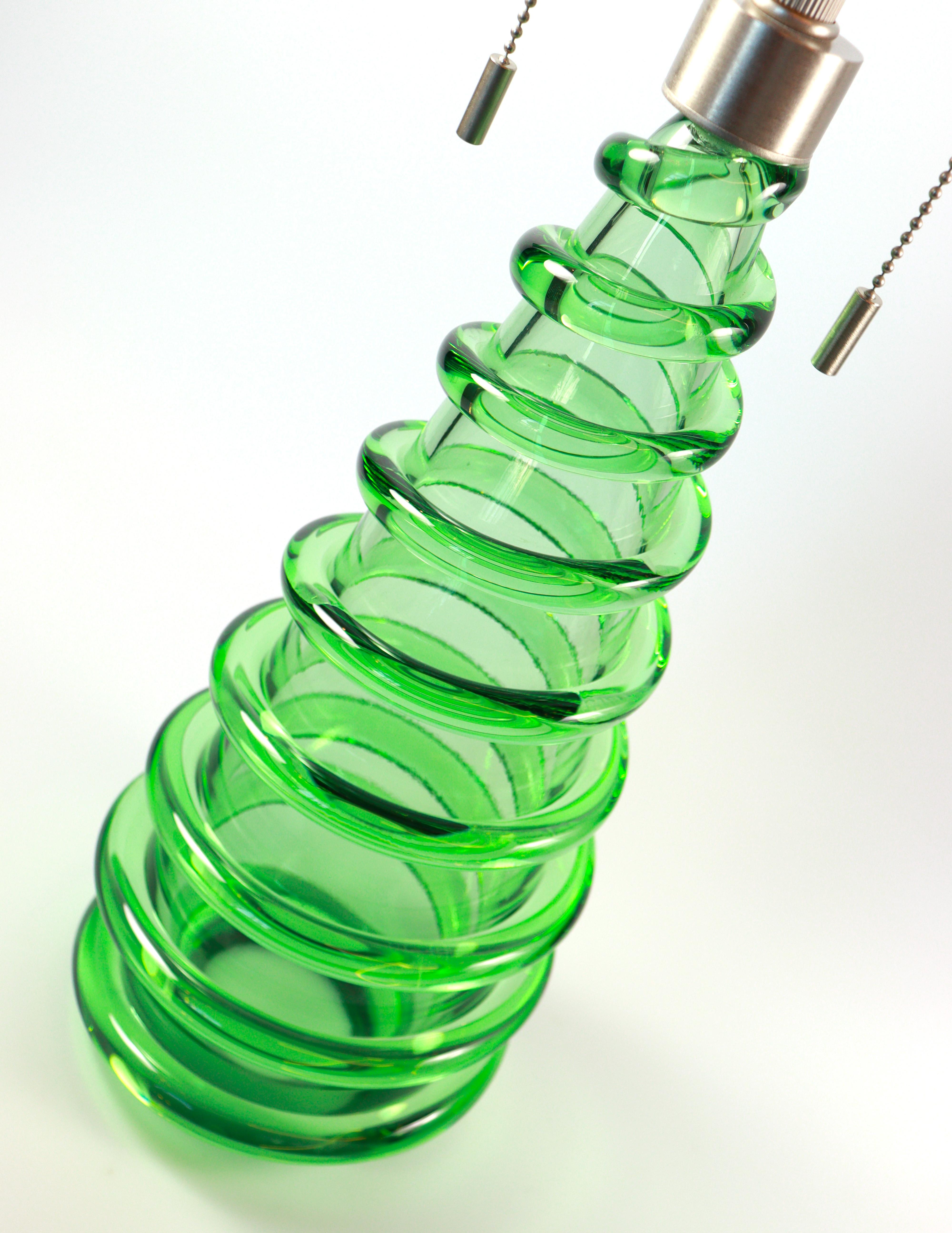 Lámpara de mesa de cristal de Murano de Seguso Vetri d'Arte. Hecha a mano con vidrio verde soplado a boca, con un tallo en forma de cono decorado con un cordón de vidrio externo en espiral aplicado en caliente. Disponible con pantalla blanca o negra