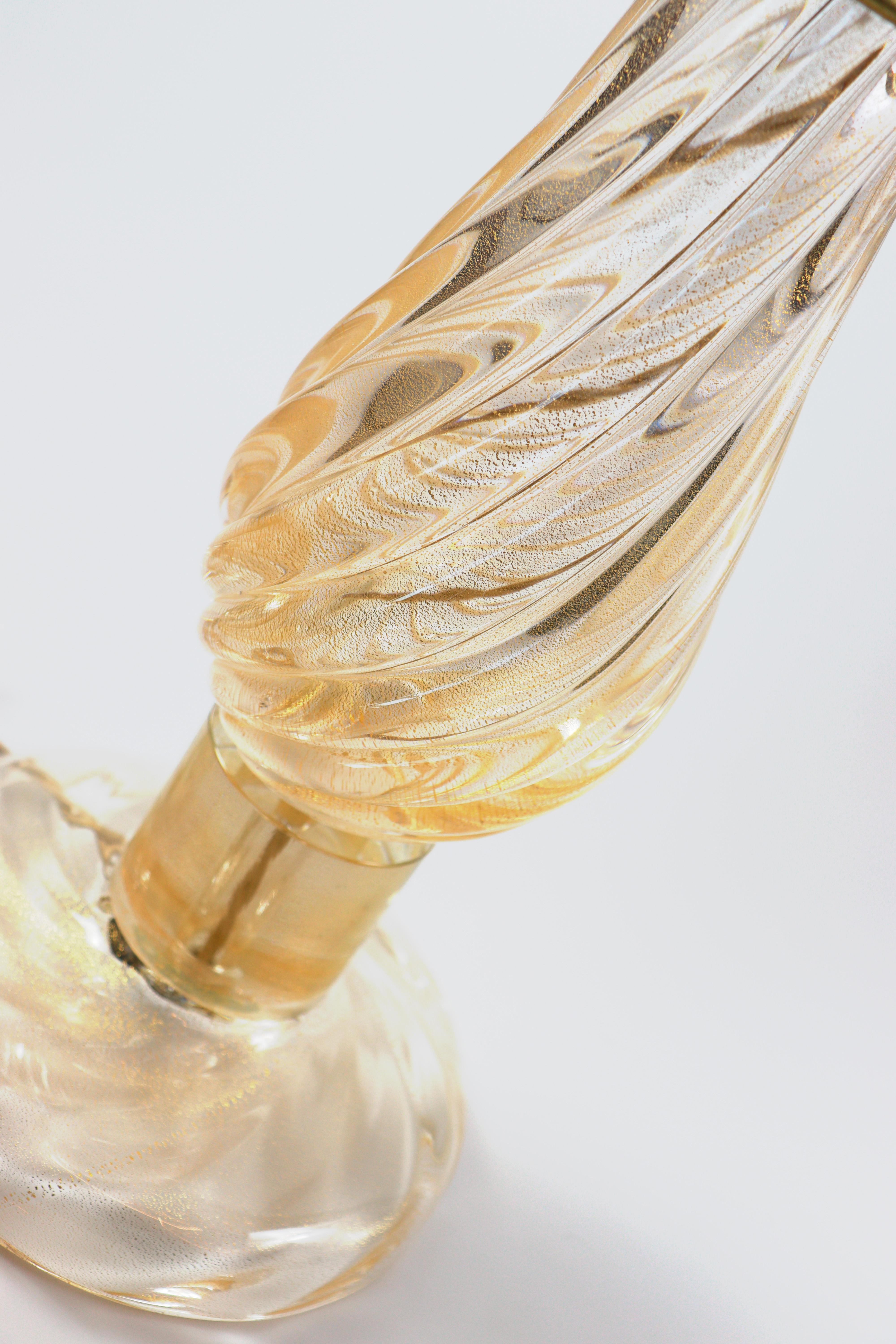Lámpara de mesa de cristal de Murano de Seguso Vetri d'Arte. Hecha a mano con vidrio dorado transparente soplado a boca, con tallo en forma de gota y base estriada. El tallo está decorado con un diseño estriado retorcido. Disponible con pantalla