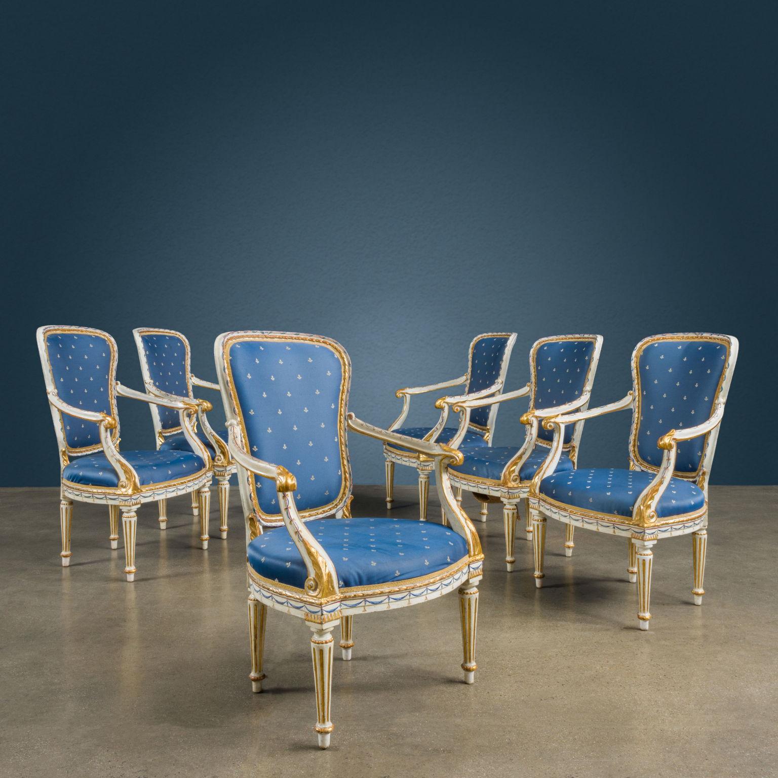 Group of six ivory lacquered, painted and gilded walnut armchairs. Shaped back; the wavy armrests are carved with an acanthus leaf, both on the socket and in the underarm, the latter is developed in a twisting motion and, laterally, the leaf ends in
