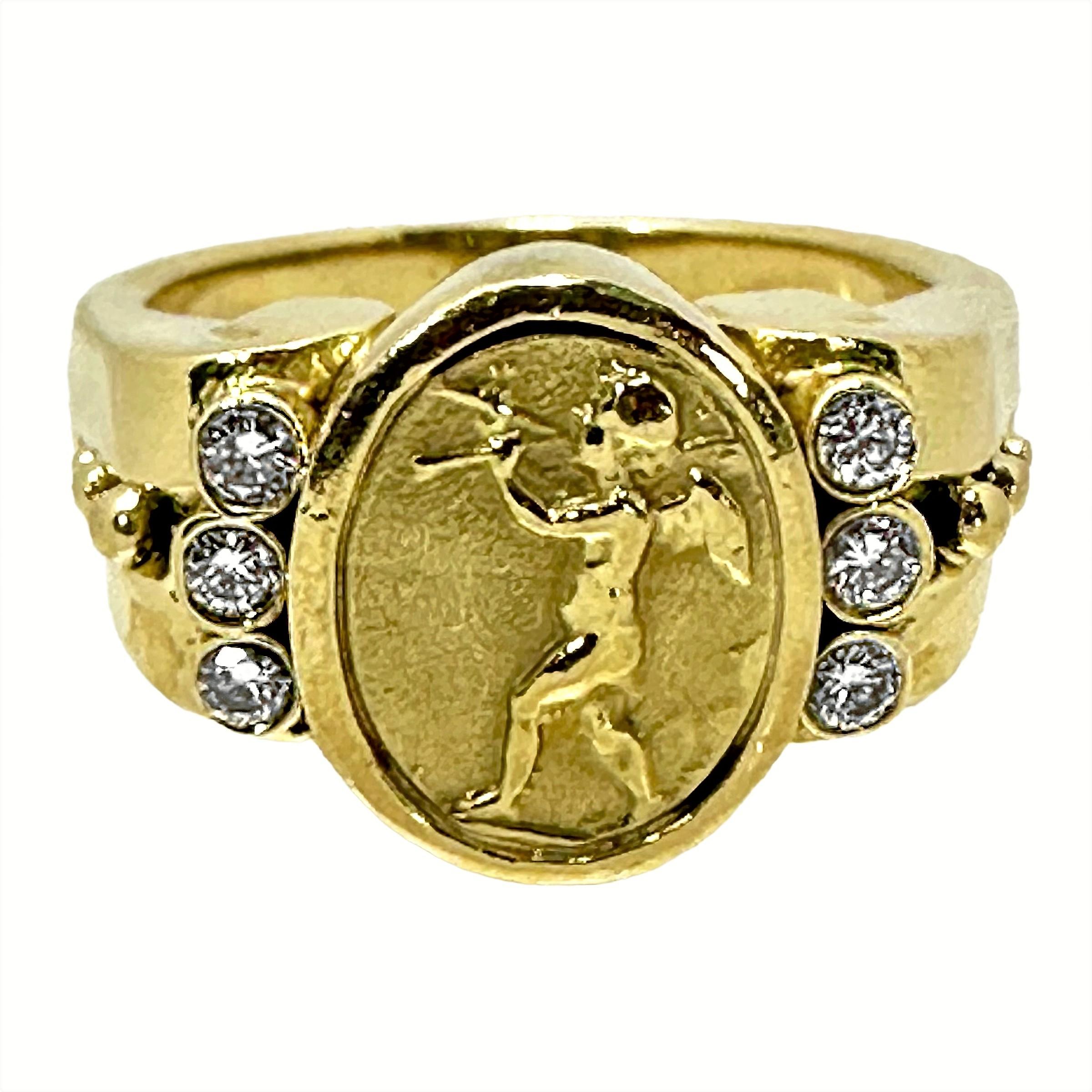 This tailored and whimsical 18K yellow gold SeidenGang designer ring features a fanciful cherub playing an ancient aulos wind instrument, in intaglio form. Flanking this central motif are six brilliant cut bezel set round brilliant cut diamonds