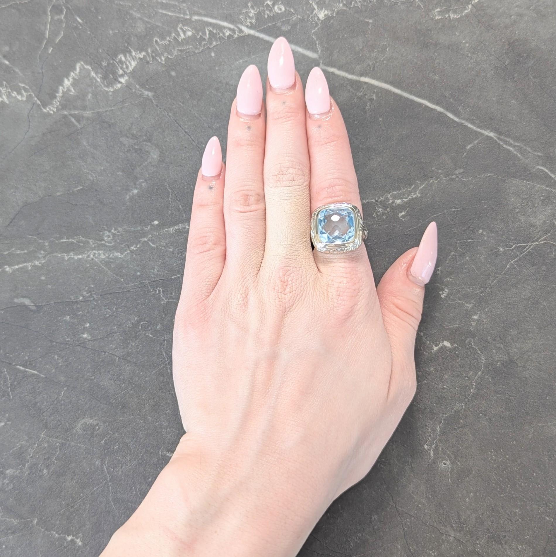 Centering a cushion shaped checkerboard cut aquamarine weighing approximately 11.40 carats
Transparent light blue in color and set in a high polish bezel with a cushion surround
Decorated with engraved scrolling foliate motif surround an
