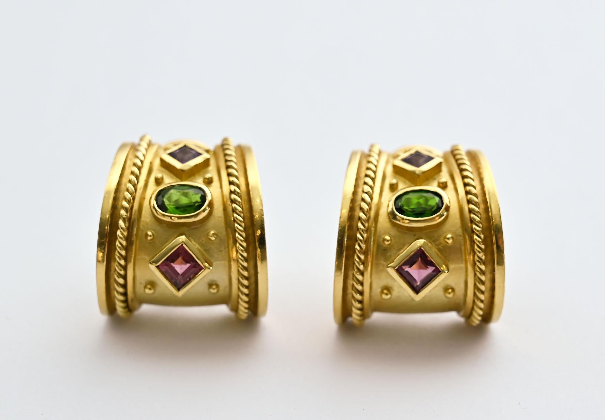 Seidengang half hoop earrings embellished with both pink and green tourmaline and an amethyst as well as gold balls and braiding. The earrings have both post and clip backs. The bottom of the earrings measures 3/4