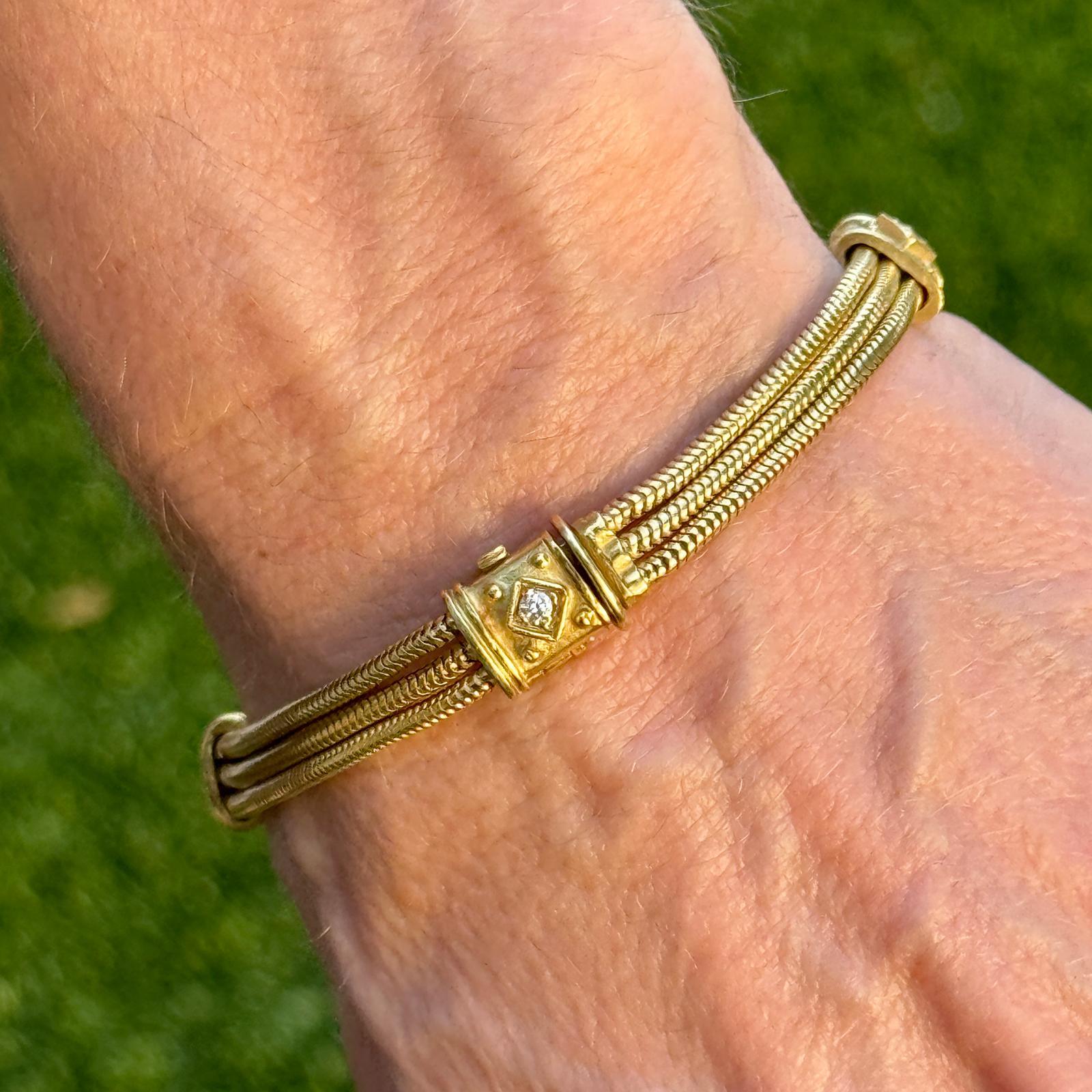 This 18 karat yellow gold SeidenGang three-row snake chain bracelet exudes timeless luxury with its fluid, woven design. Four round brilliant-cut diamonds, totaling approximately 0.20 carats with G-H color and VS2 clarity, are elegantly set within