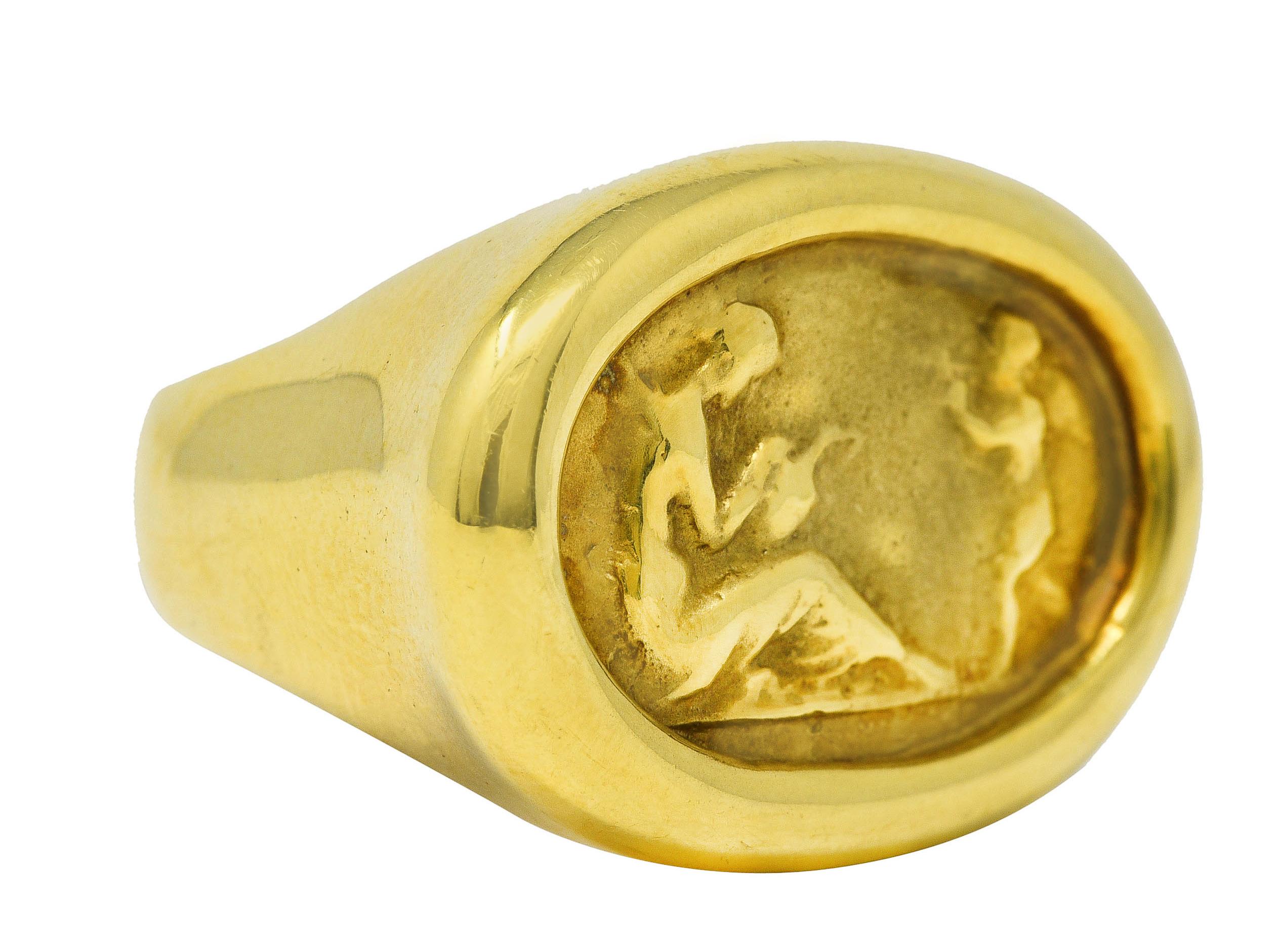 Centering an East to West repoussè of a reclining Venus holding vase with a winged Cupid

With fluted high polished gold surround

Stamped 14k for 14 karat gold

With maker's mark 

Circa: 1980's

Ring size: 6 1/2 and sizable

Measures: North to