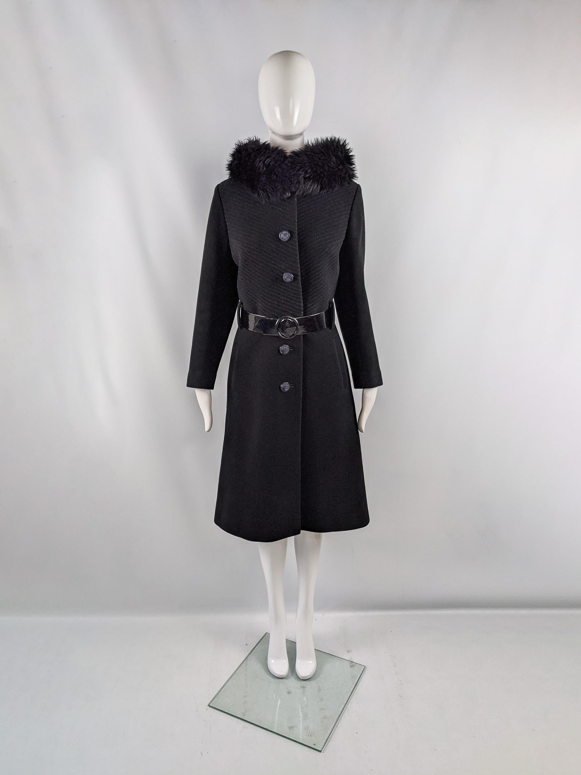 A vintage womens coat from the 60s by quality British label, Seigal. In a black wool fabric with a ribbed texture on top and a glamorous Russian princess style faux fur collar. It has a glossy vinyl belt and buttons down the front. 

Size: