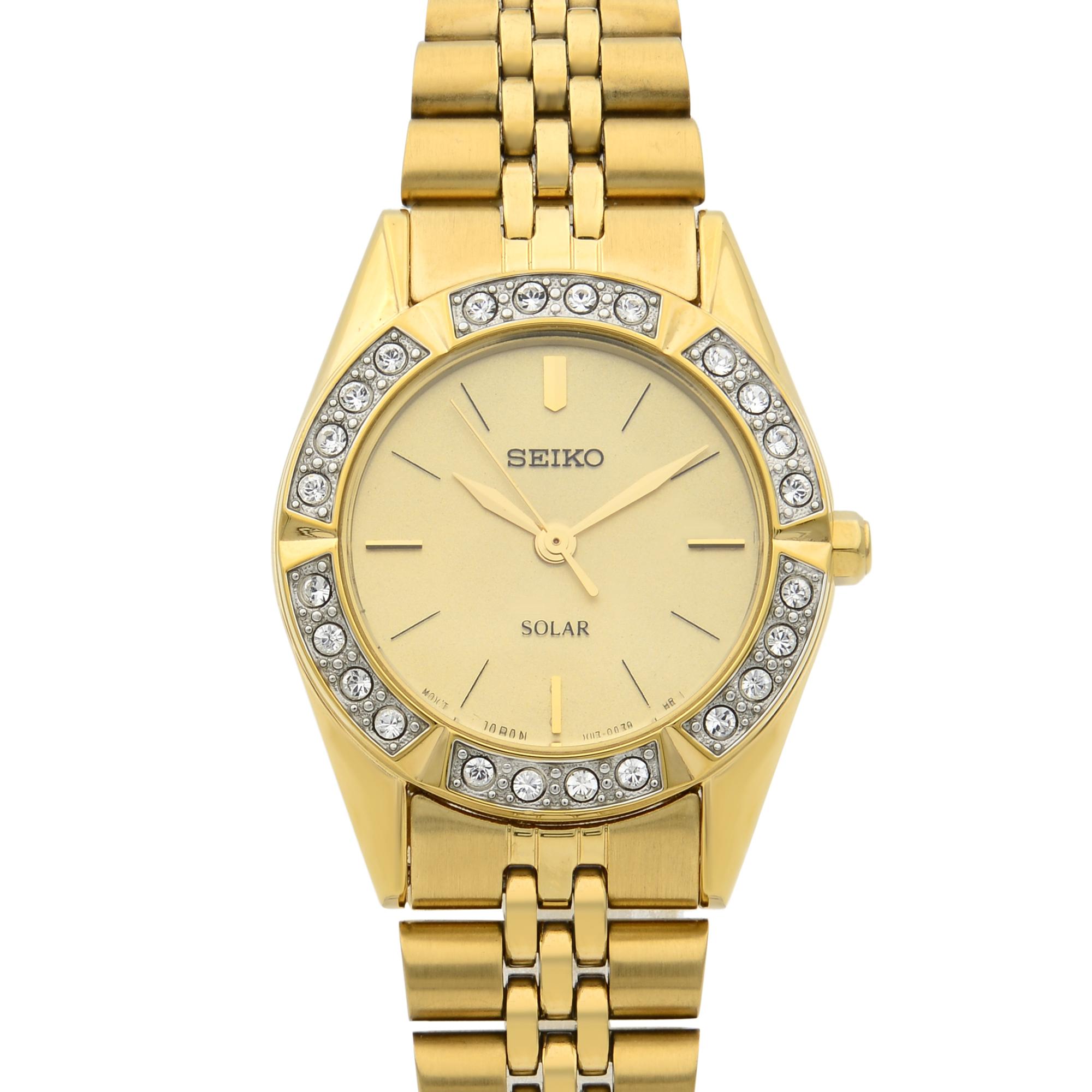 This watch is in pre-owned condition. The timepiece has minor scratches. 
Gold-tone stainless steel case and bracelet. Fixed gold-tone bezel set with Swarovski crystals. 
Champagne dial with gold-tone hands and index hour markers. Solar quartz