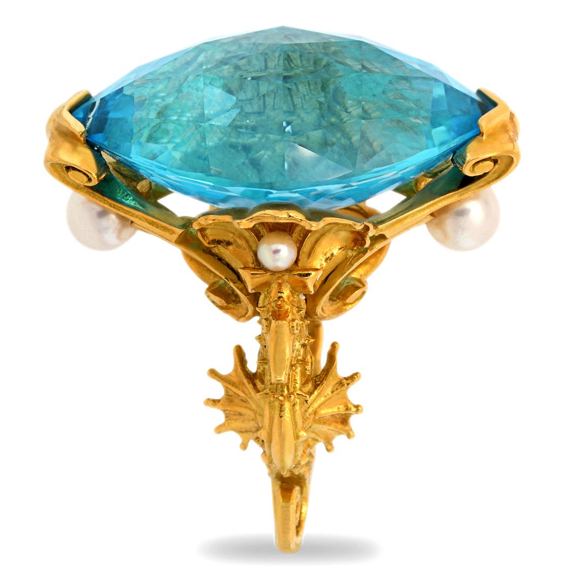 Handcrafted in 18kt yellow gold this captivating ring features a spectacular 52.3ct 31.14mm x 19.50mm x 14.06mm Swiss blue marquise checkerboard cut topaz buoyed upon golden seashells and flanked by two sentinel seahorses. It features four beautiful
