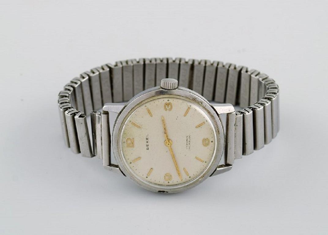 Sekel wristwatch with manual winding. Mid-20th century.
Case diameter: 35 mm.
Defective joint in the bracelet and superficial scratches in the glass.
No guarantee for the function of the watch.
Stamped.